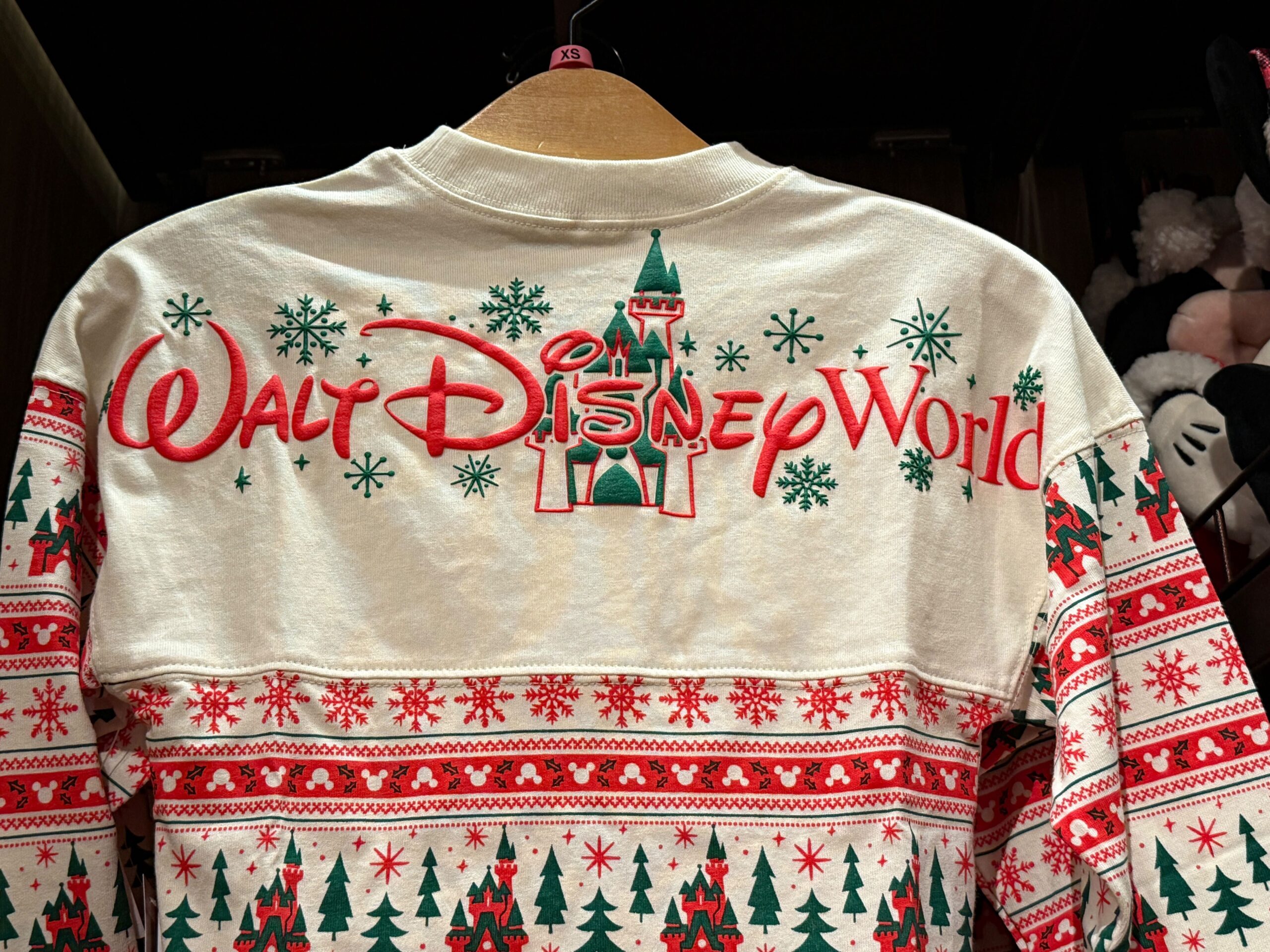 A festive 2025 Walt Disney World sweatshirt with Christmas trees, snowflakes, and a castle design on the back.