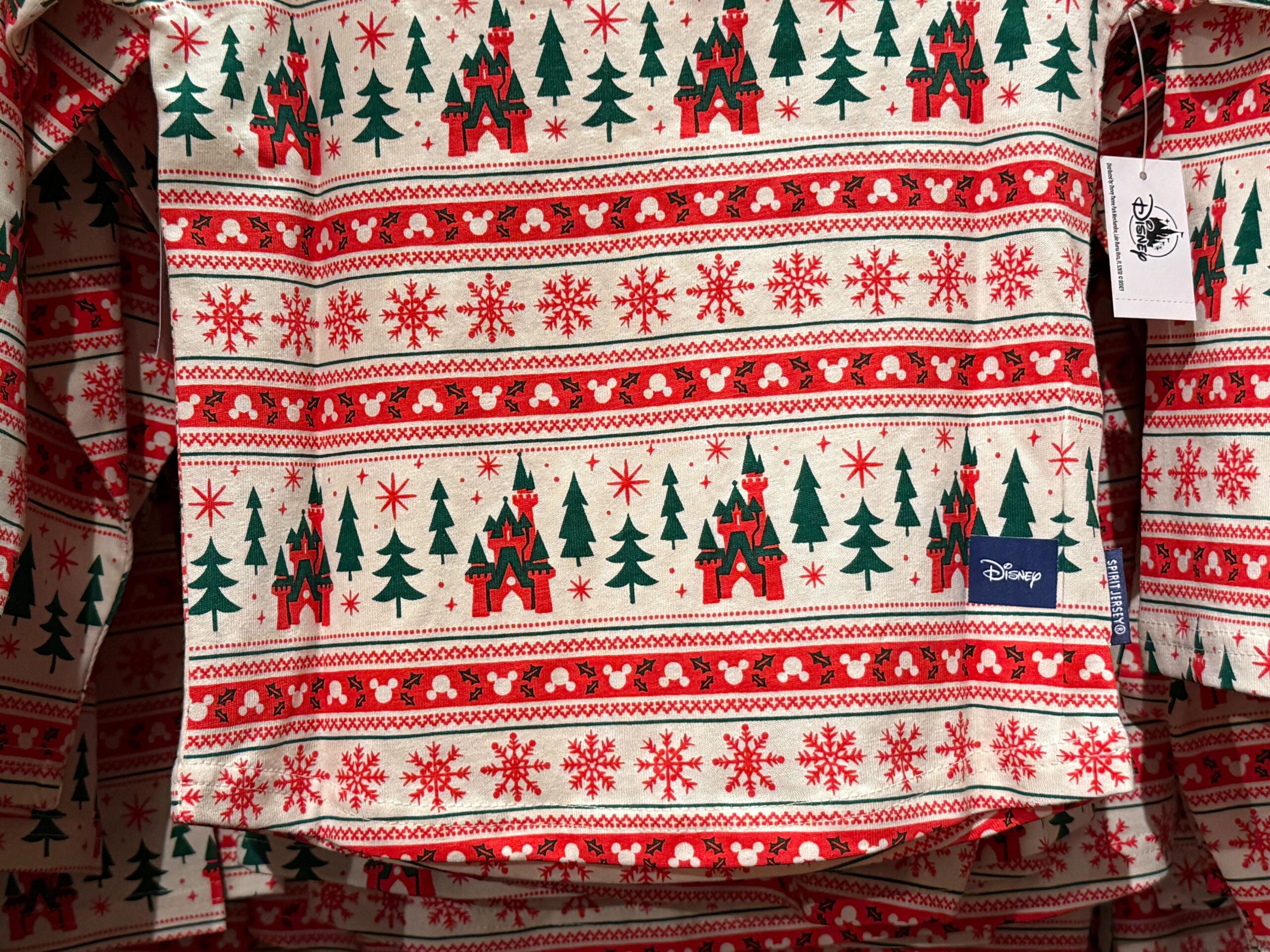 Red and green holiday shirt featuring Christmas trees, snowflakes, and Walt Disney World castle patterns on a cream background.