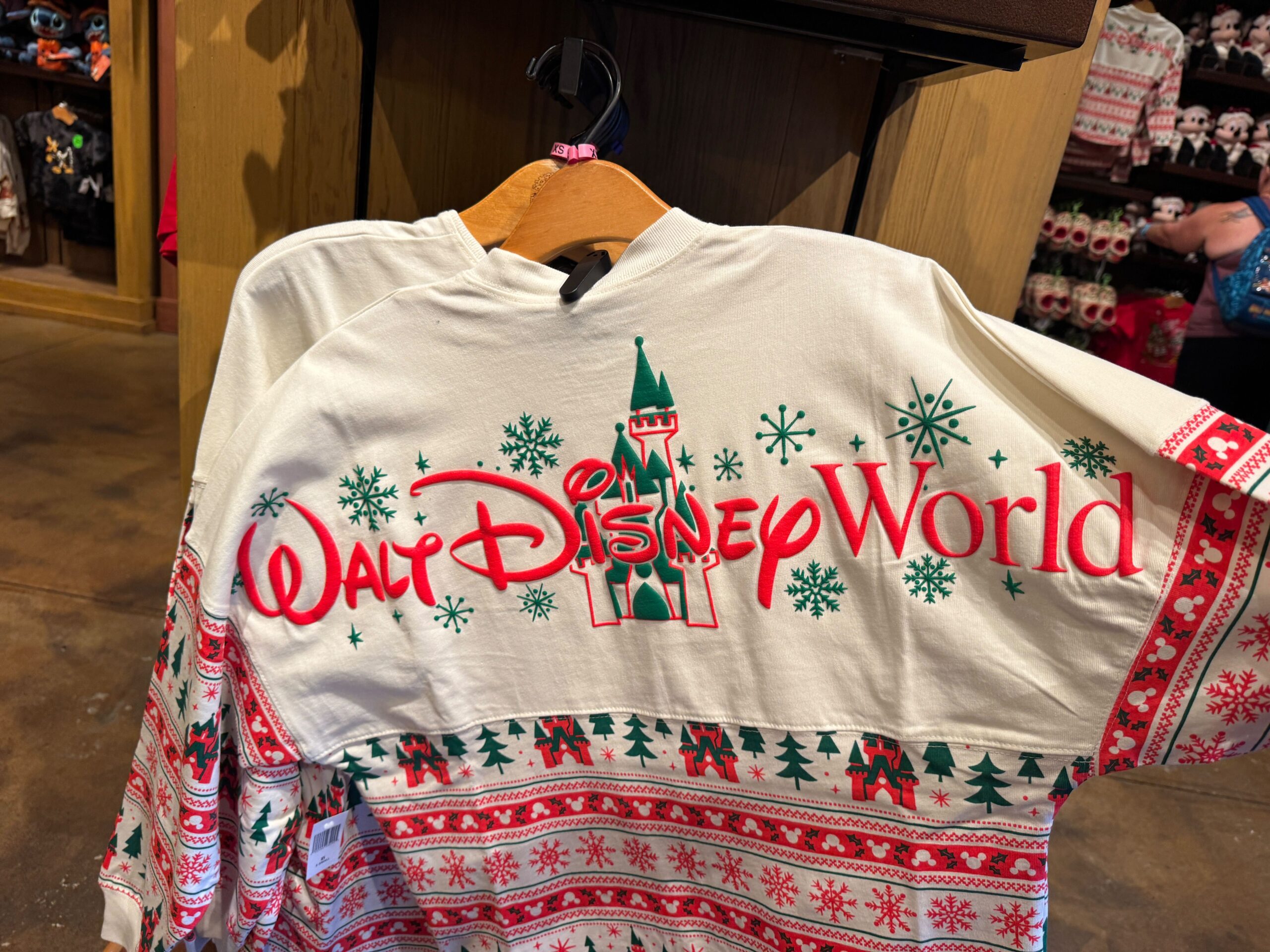A festive Walt Disney World sweatshirt, part of the 2025 Disney merchandise holiday collection, with red and green patterns.