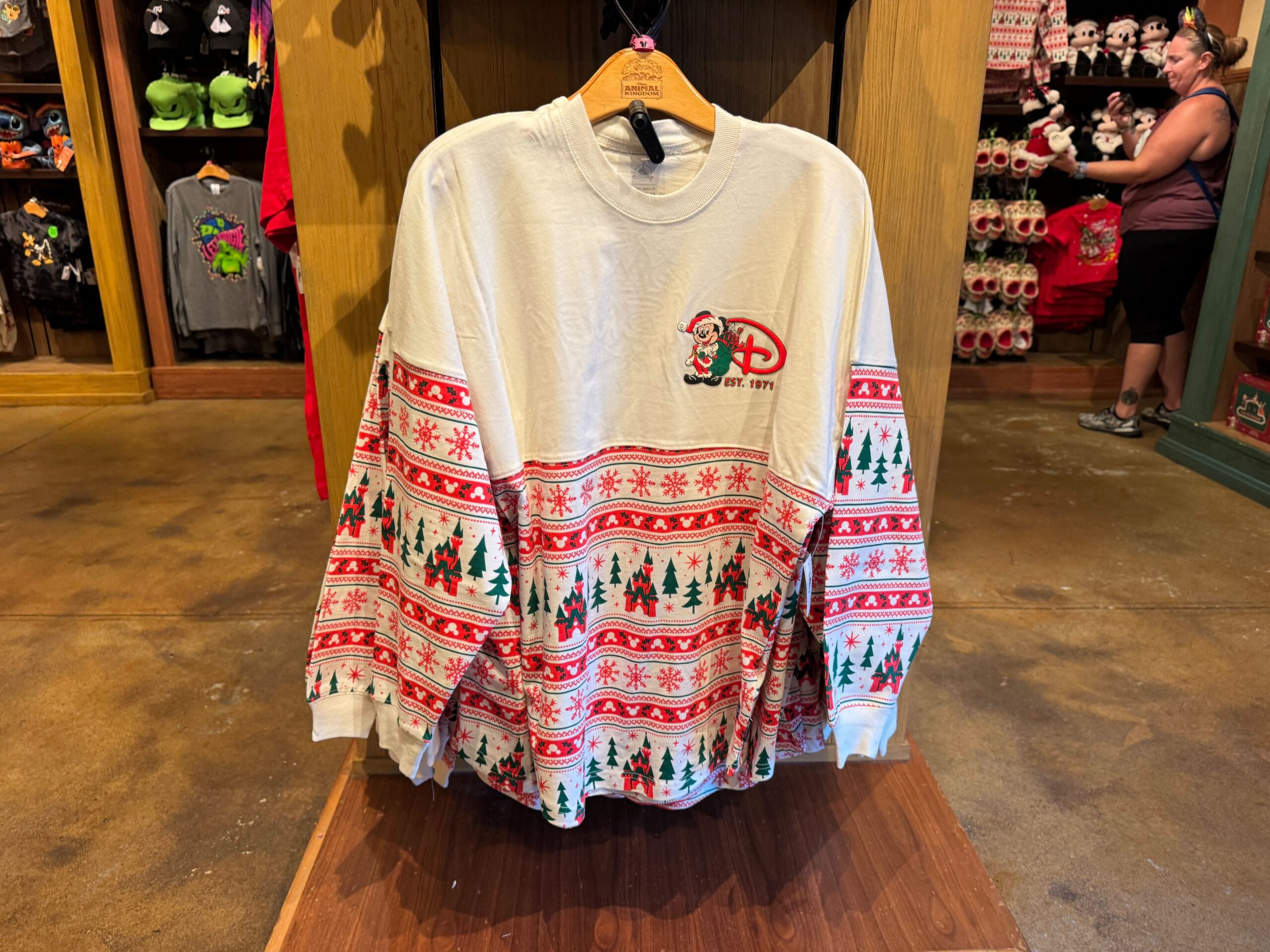 White holiday sweatshirt with Disney logo, Santa hat, and Christmas trees—2025 Christmas merchandise at Walt Disney World.