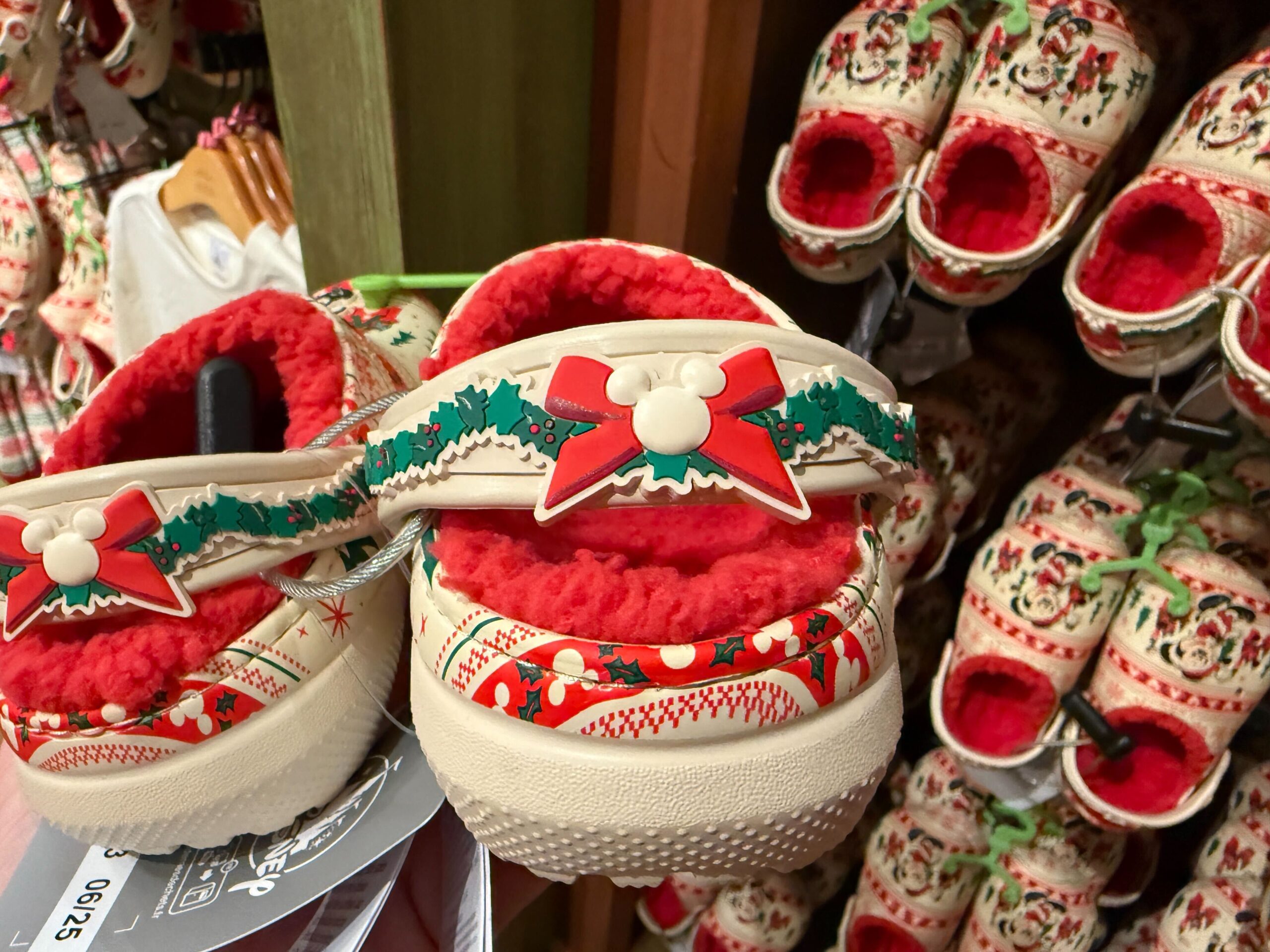 Holiday-themed clogs with red fleece and holly, part of the 2025 Walt Disney World Christmas merchandise collection.