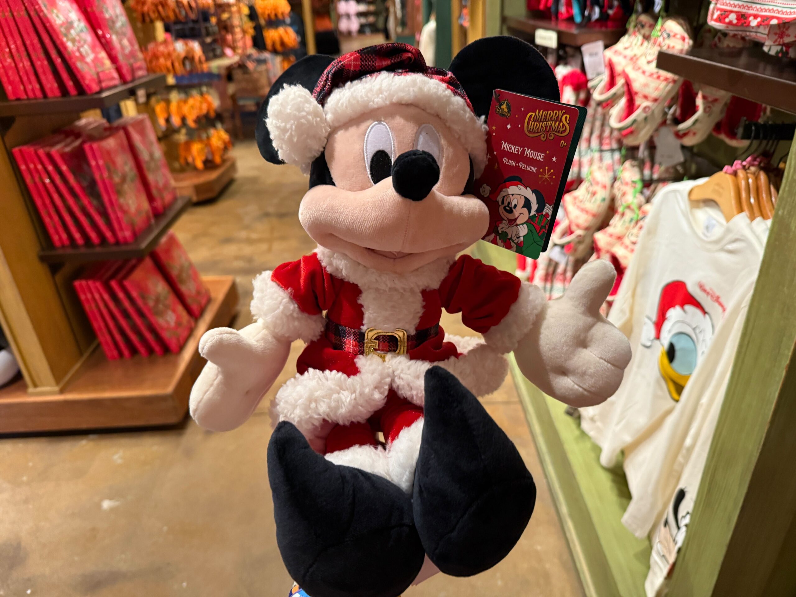 Plush Mickey Mouse in a Santa outfit, featured as Disney World Christmas merchandise in a festive store display.