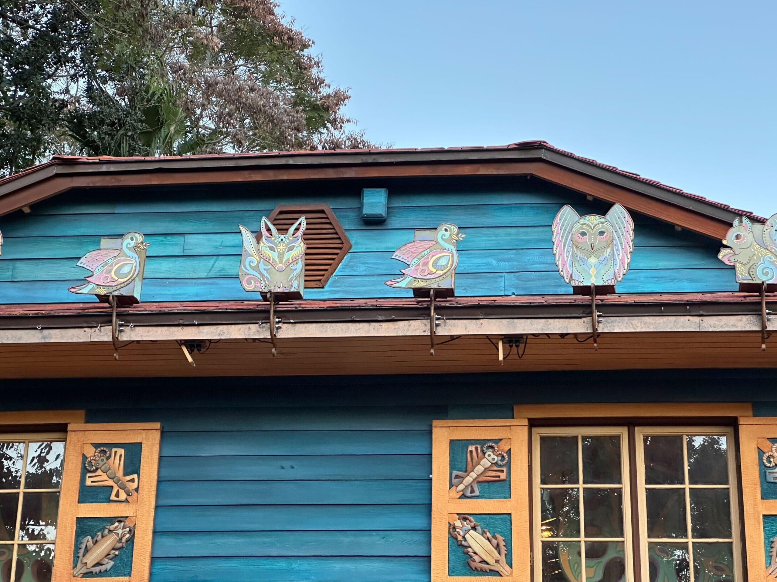 Blue wooden structure adorned with vibrant bird and owl decor, evoking Disney's Animal Kingdom ambiance—not a castle comparison here.