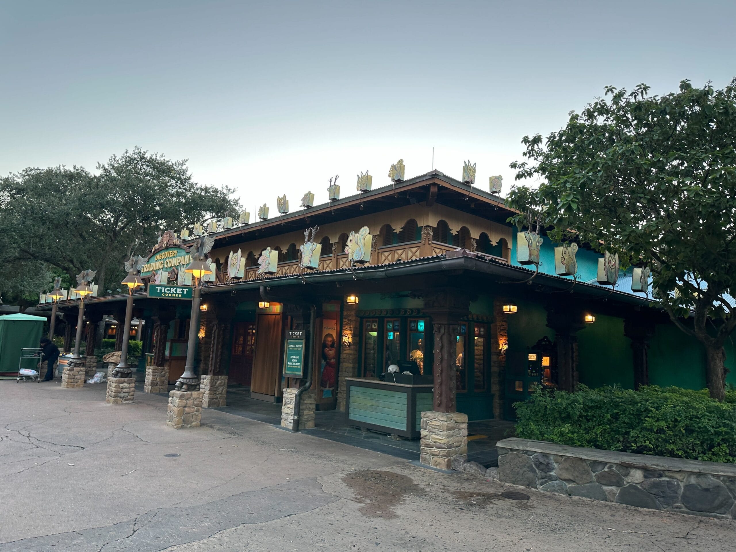 Festive ticket building with animal figures and holiday lights at sunrise in Animal Kingdom, no castle like Magic Kingdom’s Cinderella Castle.