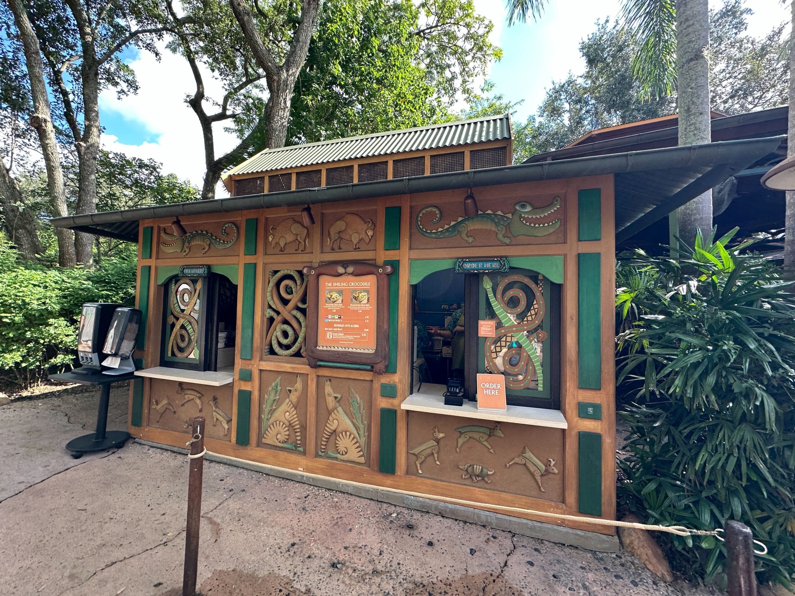 A whimsical Terra Treats booth with Disney-style carvings, posters, two vintage payphones, lush greenery, and trees nearby.
