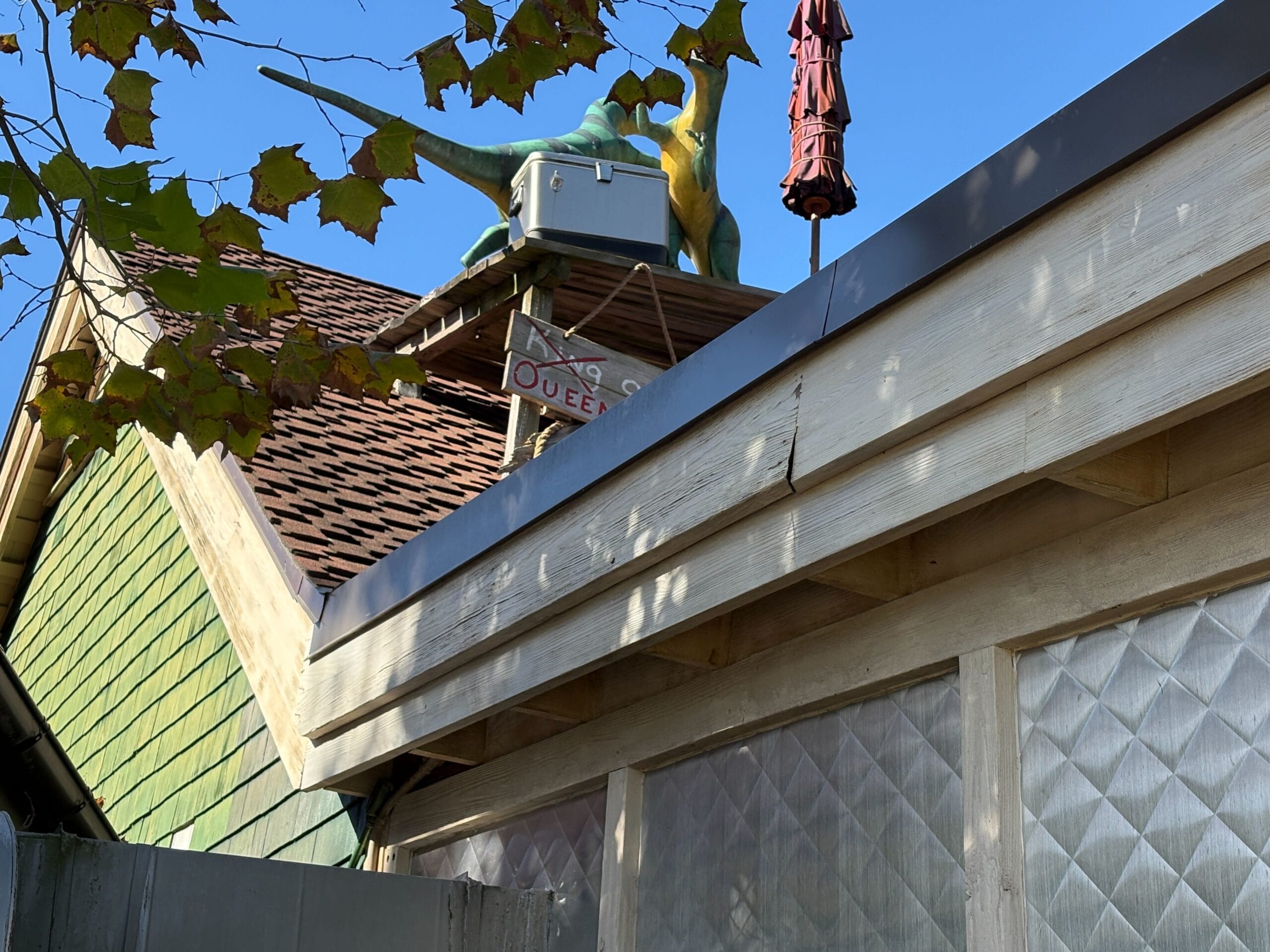 A green and yellow dinosaur statue stands atop a rooftop by Dino Bite Snacks in Disney’s Animal Kingdom, not far from the Tree of Life.