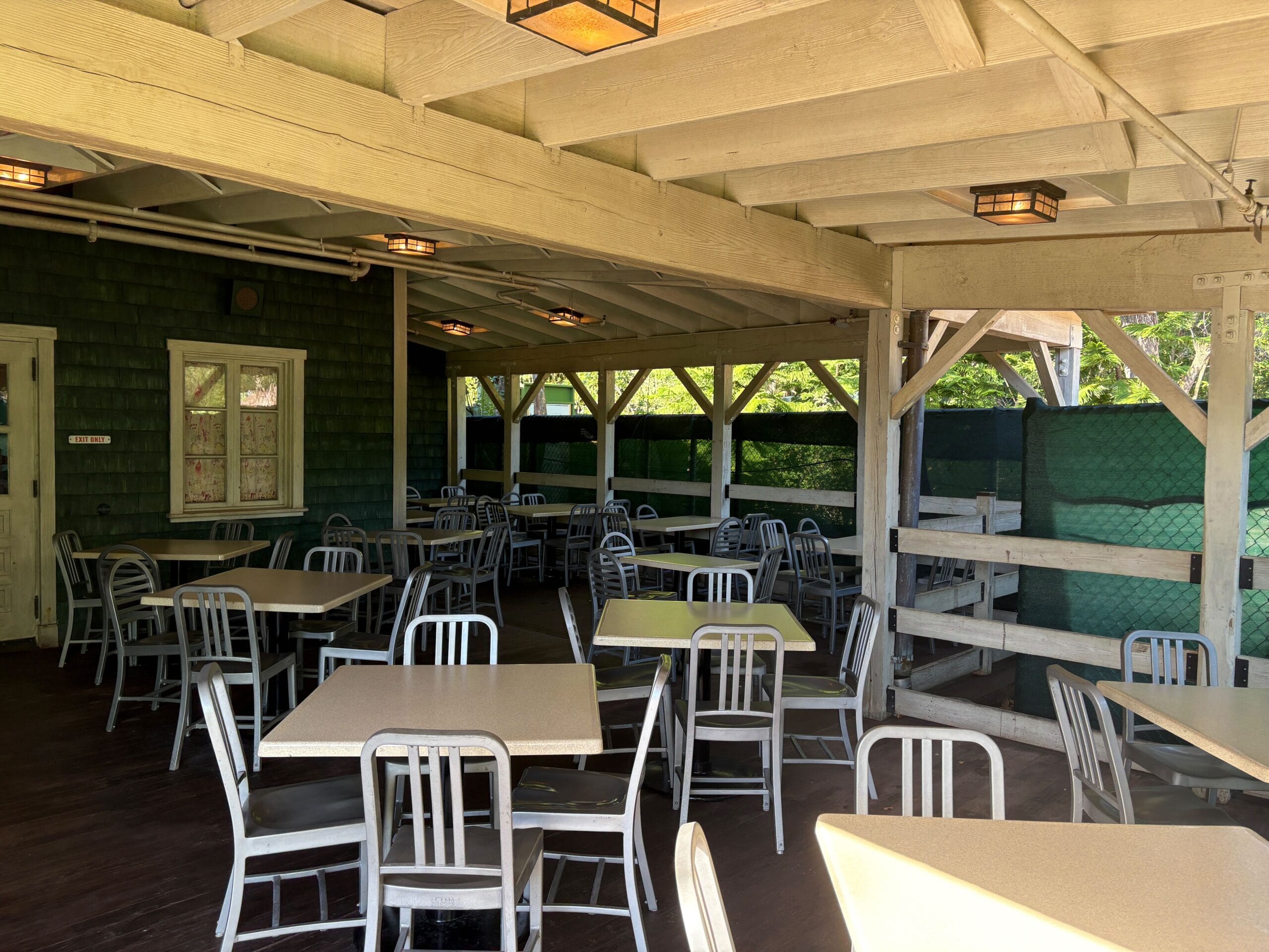 Open-air patio with unoccupied tables and metal chairs at Trilo-Bites, nestled in Disney's Animal Kingdom—no castle views here.