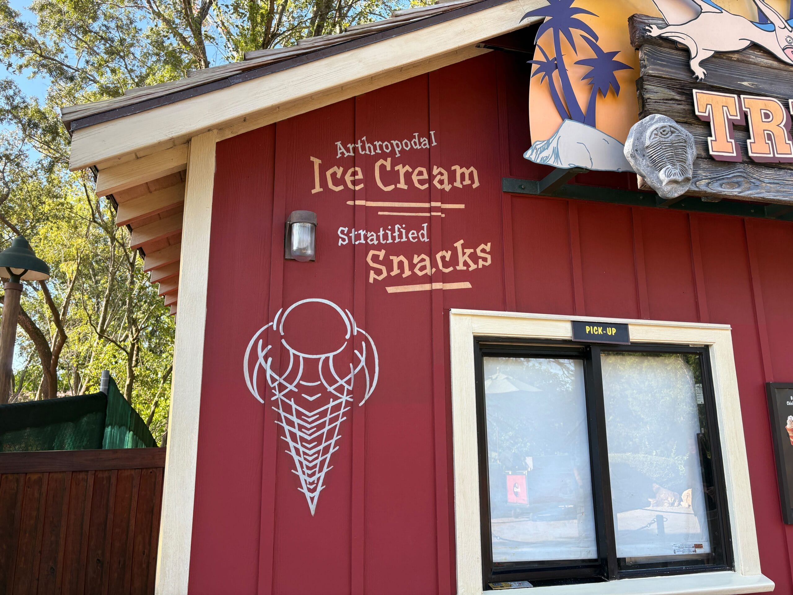 Red snack stand in Disney’s Animal Kingdom with a white trilobite and “Trilo-Bites Stratified Snacks” sign—no castle present.