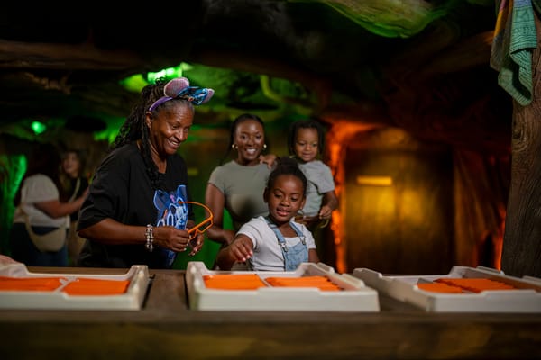 A smiling family enjoys hands-on Zootopia exhibits indoors at a Disney park, with kids playing just steps from whimsical displays.