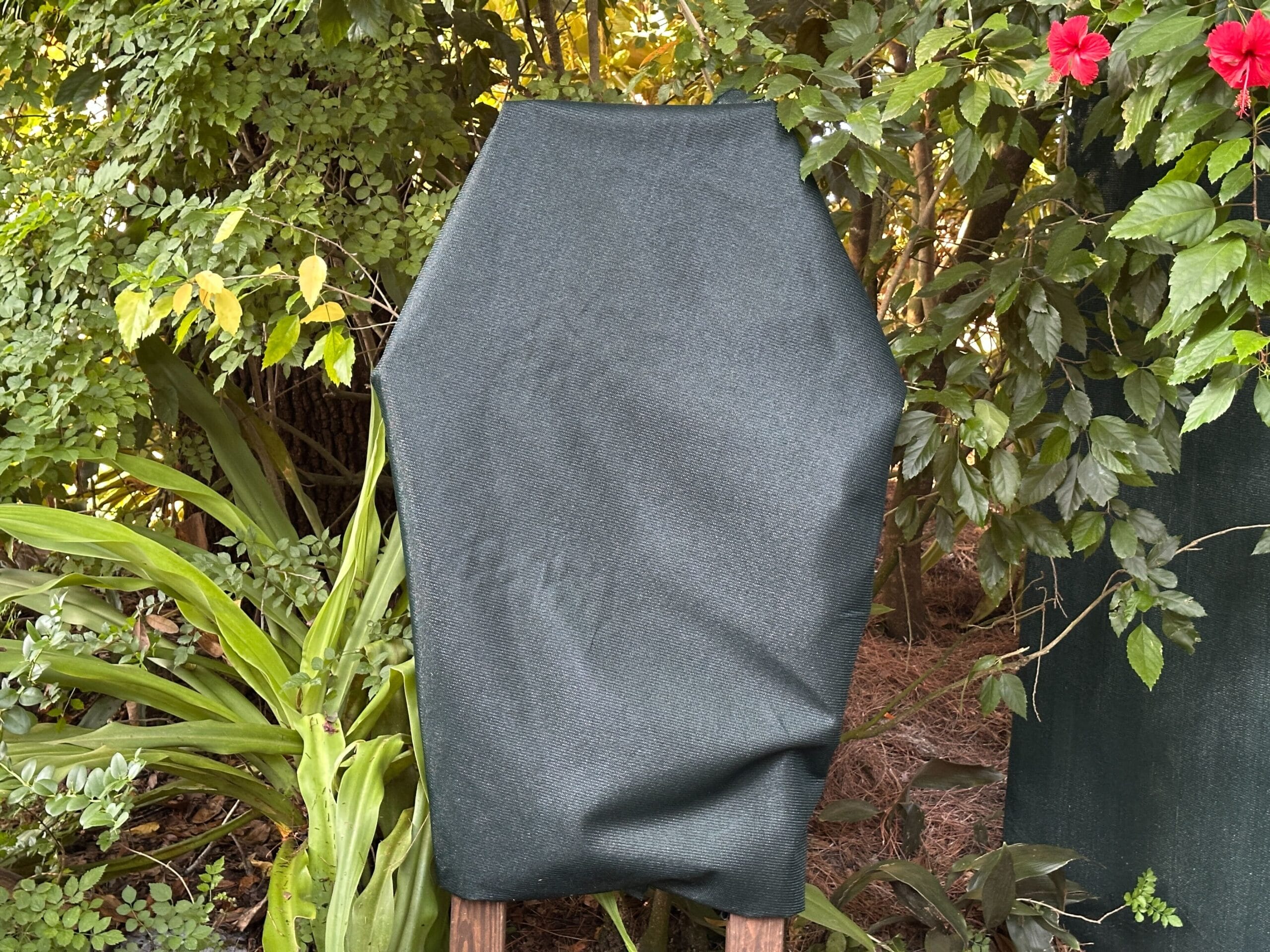 A tall garden plant draped in dark green fabric stands watch, evoking Zootopia near vibrant blooms—Disney magic in every leaf.