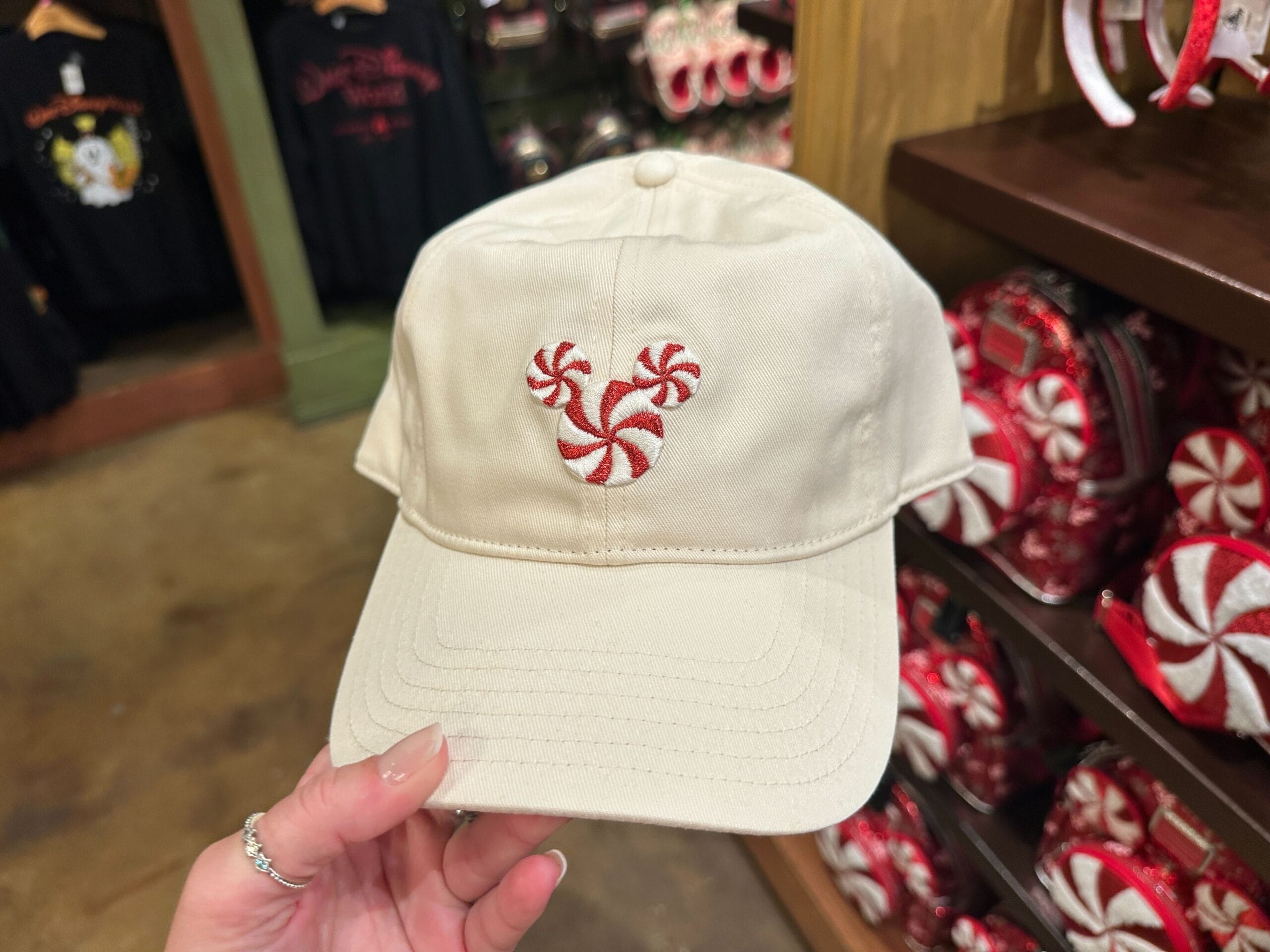 Beige cap featuring a red and white peppermint Mickey Mouse, a festive look that's right at home in any Disney park for the holidays.