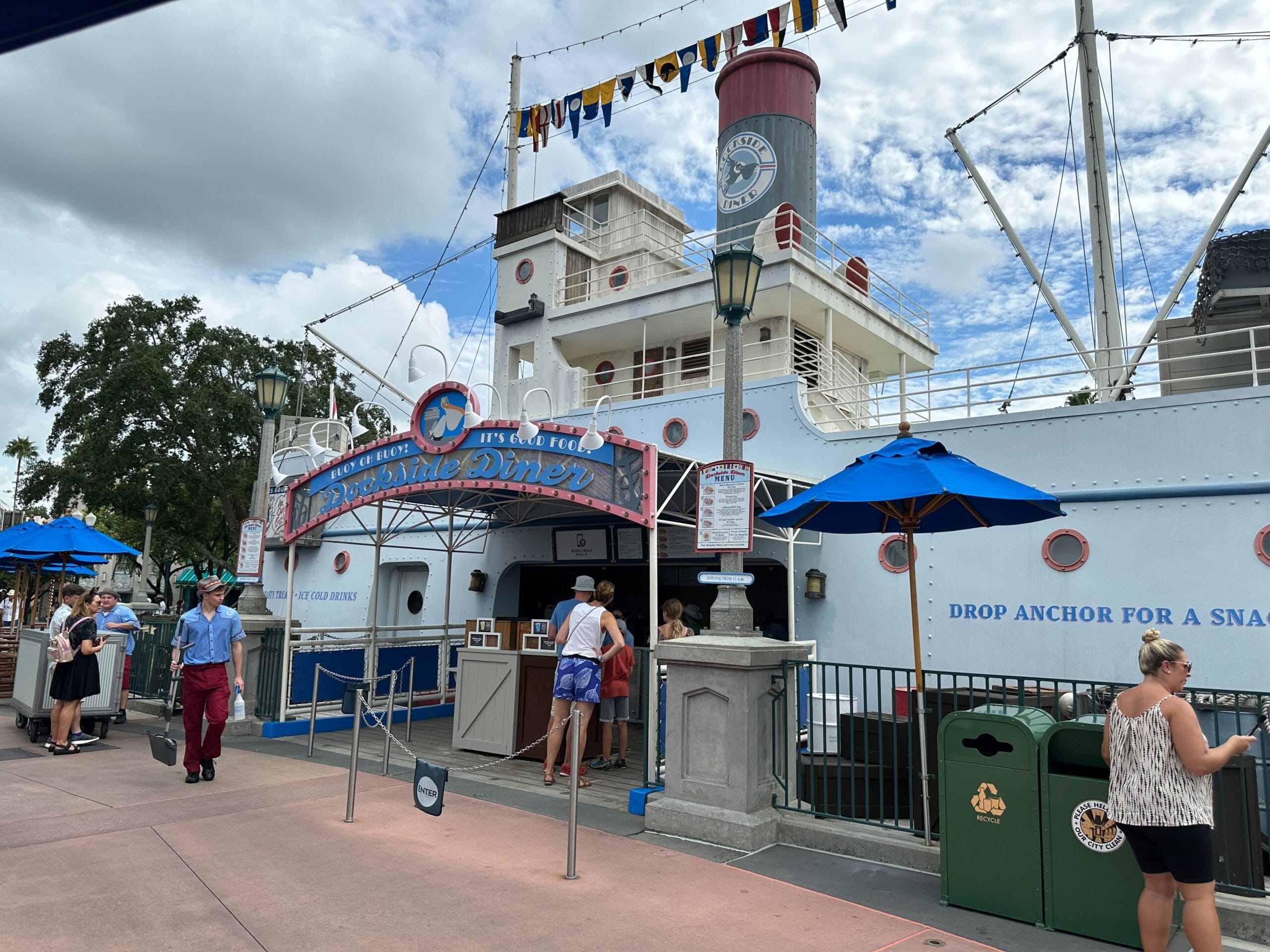 Guests gather outside Dockside Diner during Jollywood Nights at Disney's Hollywood Studios, under bright blue umbrellas.