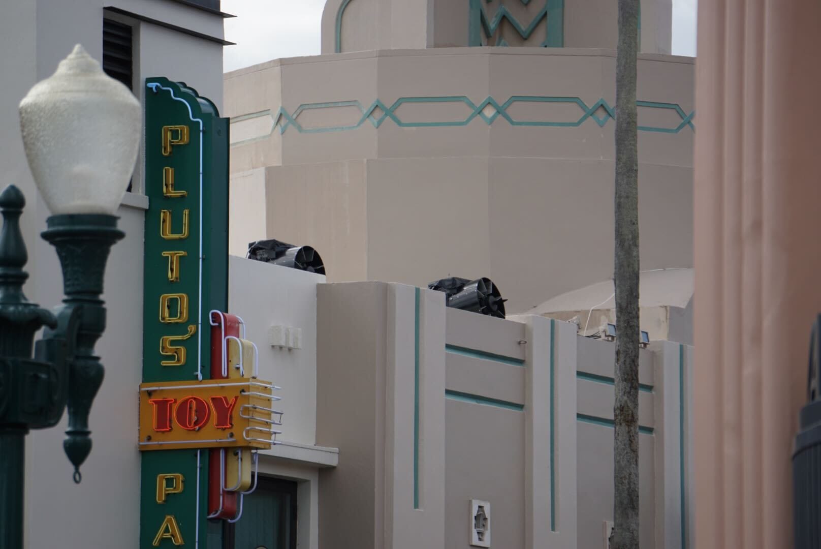 A retro "PLUTO’S TOY PALACE" sign on a pastel art-deco facade at Disney's Hollywood Studios; no castle like Disney parks' icons in view.