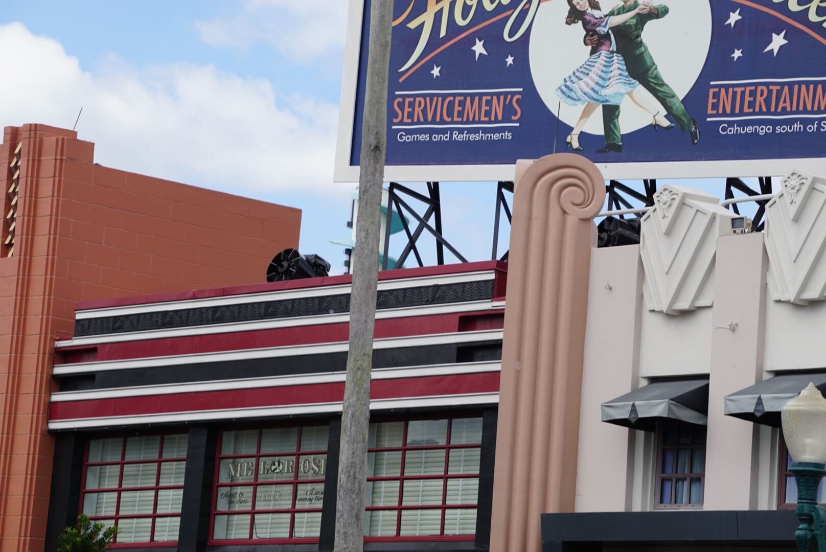Art deco building in Hollywood Studios with red and cream accents, vintage signage, and festive holiday decorations—no castle shown.