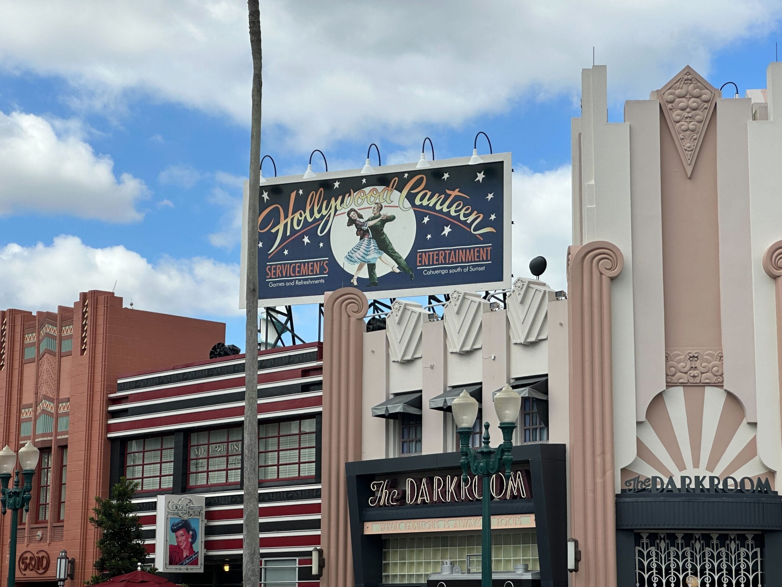 Art deco Hollywood Studios buildings with a “Hollywood Canteen” sign, evoking classic Disney park theming, under a cloudy sky.