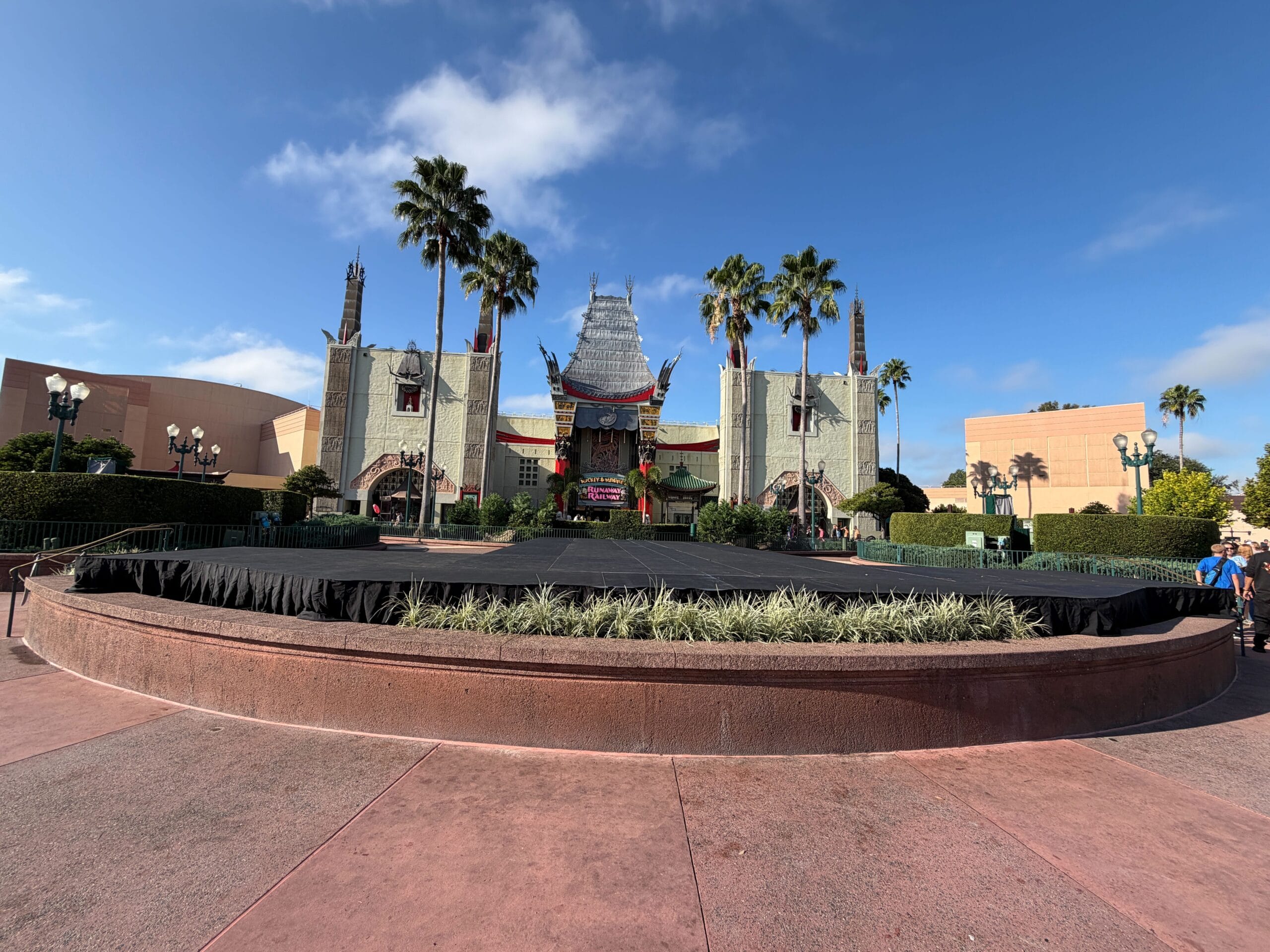 The Chinese Theatre at Disney’s Hollywood Studios lit for Jollywood Nights, palm trees and stage beneath blue sky.