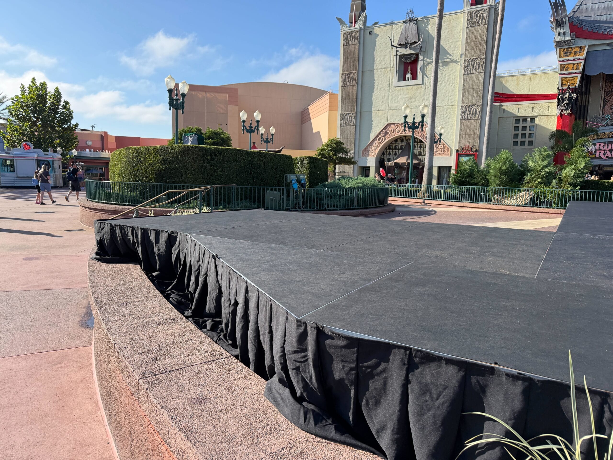 Black stage with draped skirt outdoors at Hollywood Studios in front of a grand theater.