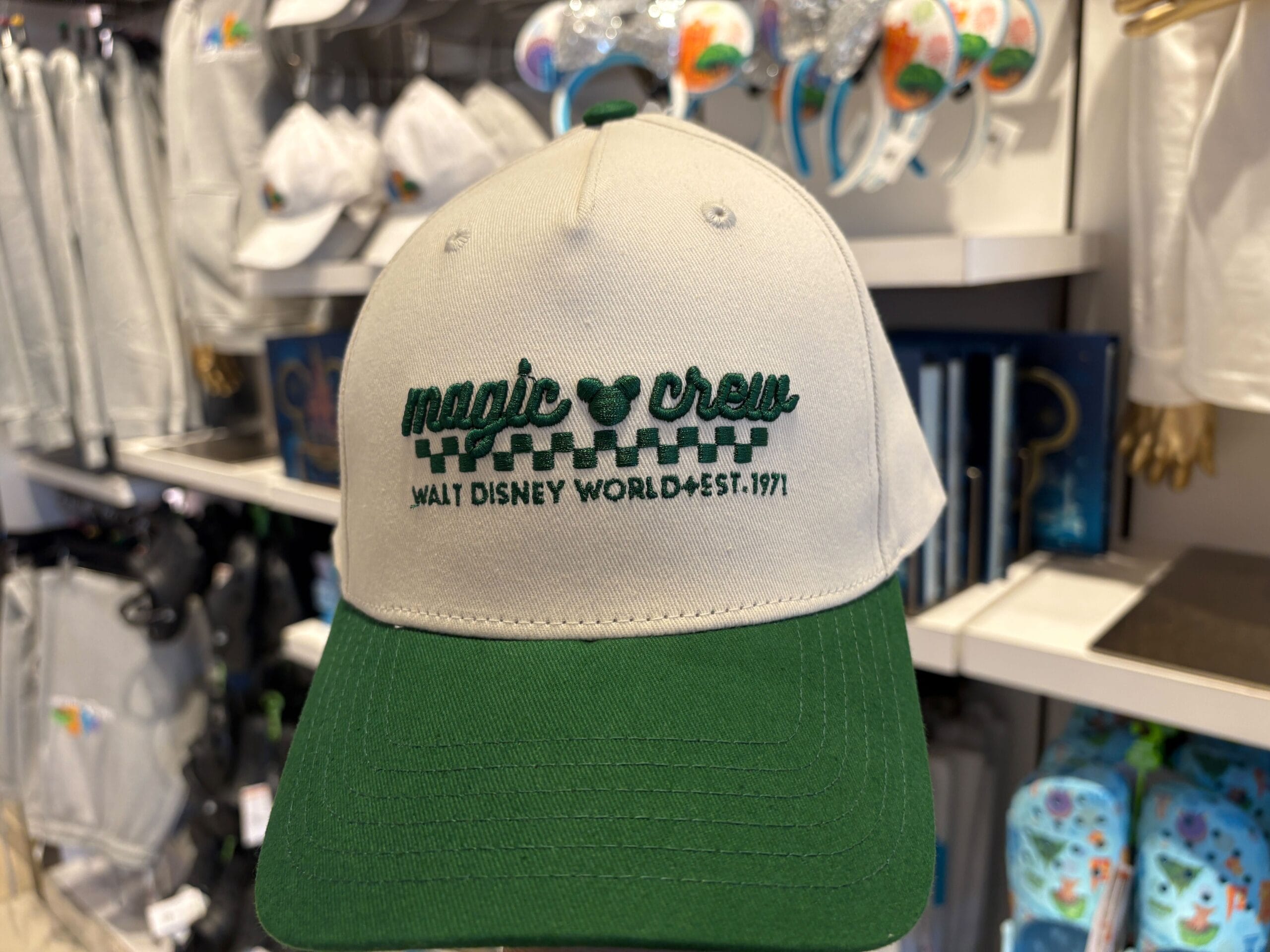 A green and white cap displays "magic crew Walt Disney World est. 1971" with a Mickey Mouse icon, referencing Florida's park.