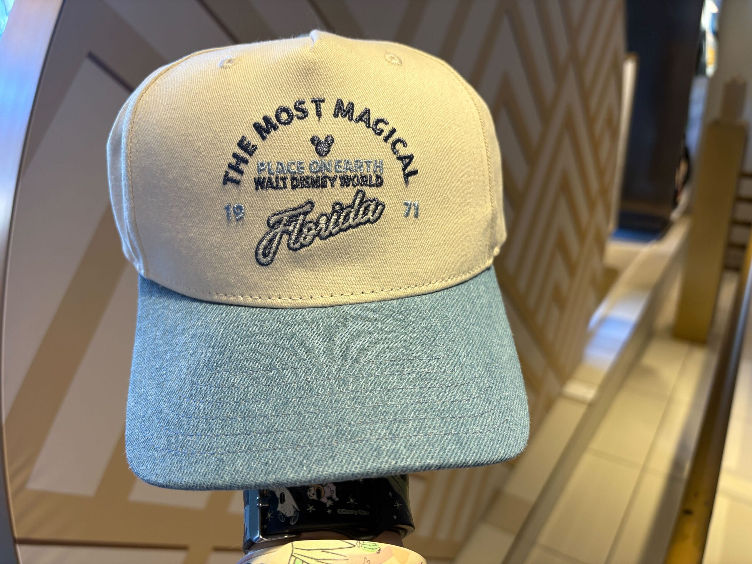 A cream and blue cap embroidered with "The Most Magical Place on Earth, Walt Disney World, Florida," referencing the iconic Cinderella Castle unique to Walt Disney World compared to castles in other Disney parks.