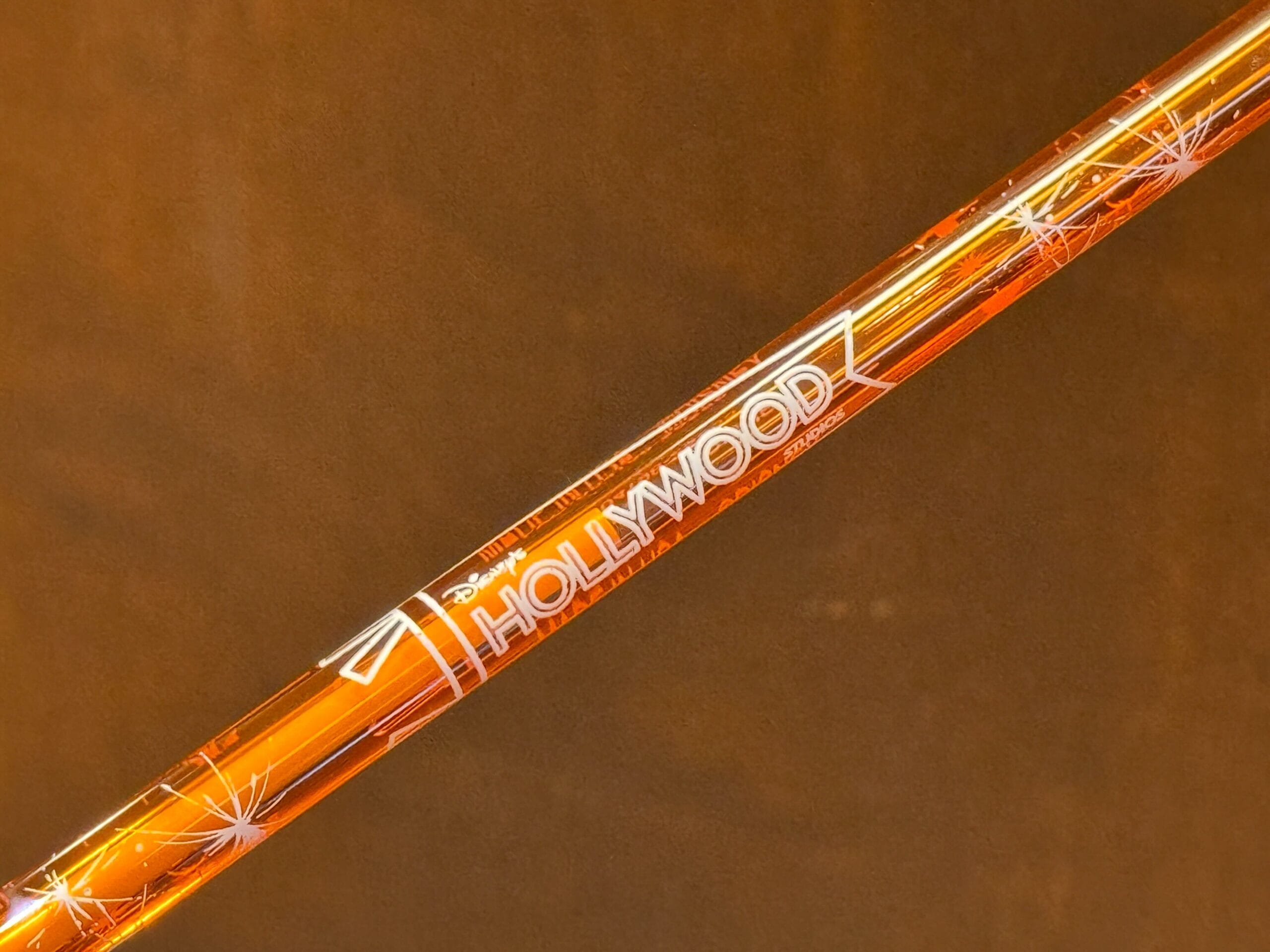 Close-up of an orange stick with "HOLLYWOOD" and white starbursts on brown, reminiscent of classic Disney Hollywood Studios design.