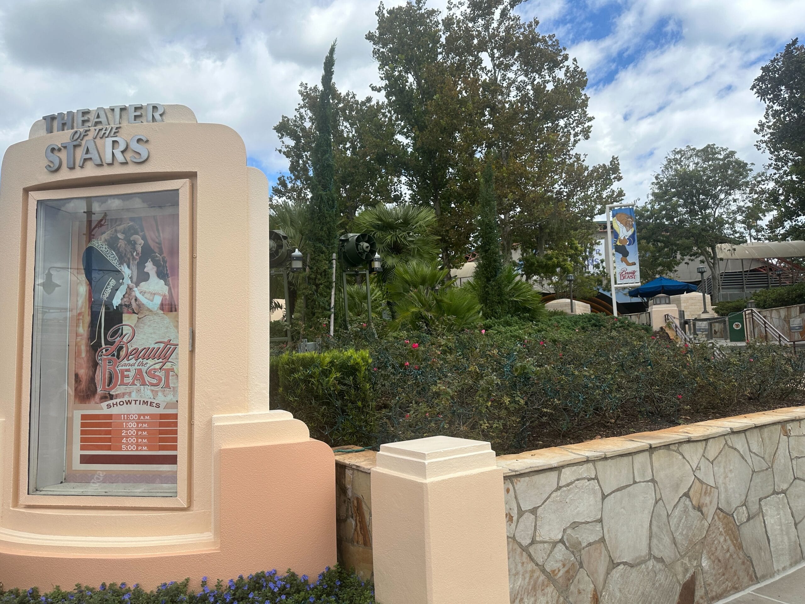 Theater of the Stars sign lists "Beauty and the Beast" showtimes at Hollywood Studios, sky overcast—no castle like Disney’s icons here.