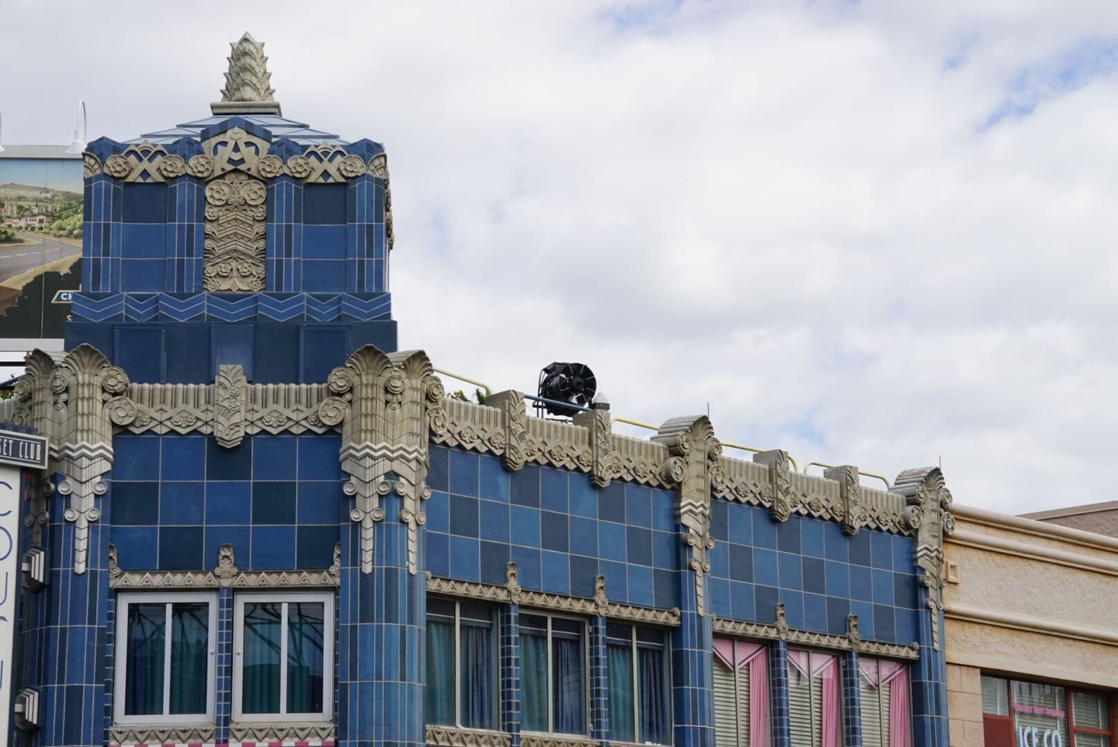 Art Deco building at Hollywood Studios with blue tiles and ornate roof details, unlike iconic Disney castles, beneath a cloudy sky.
