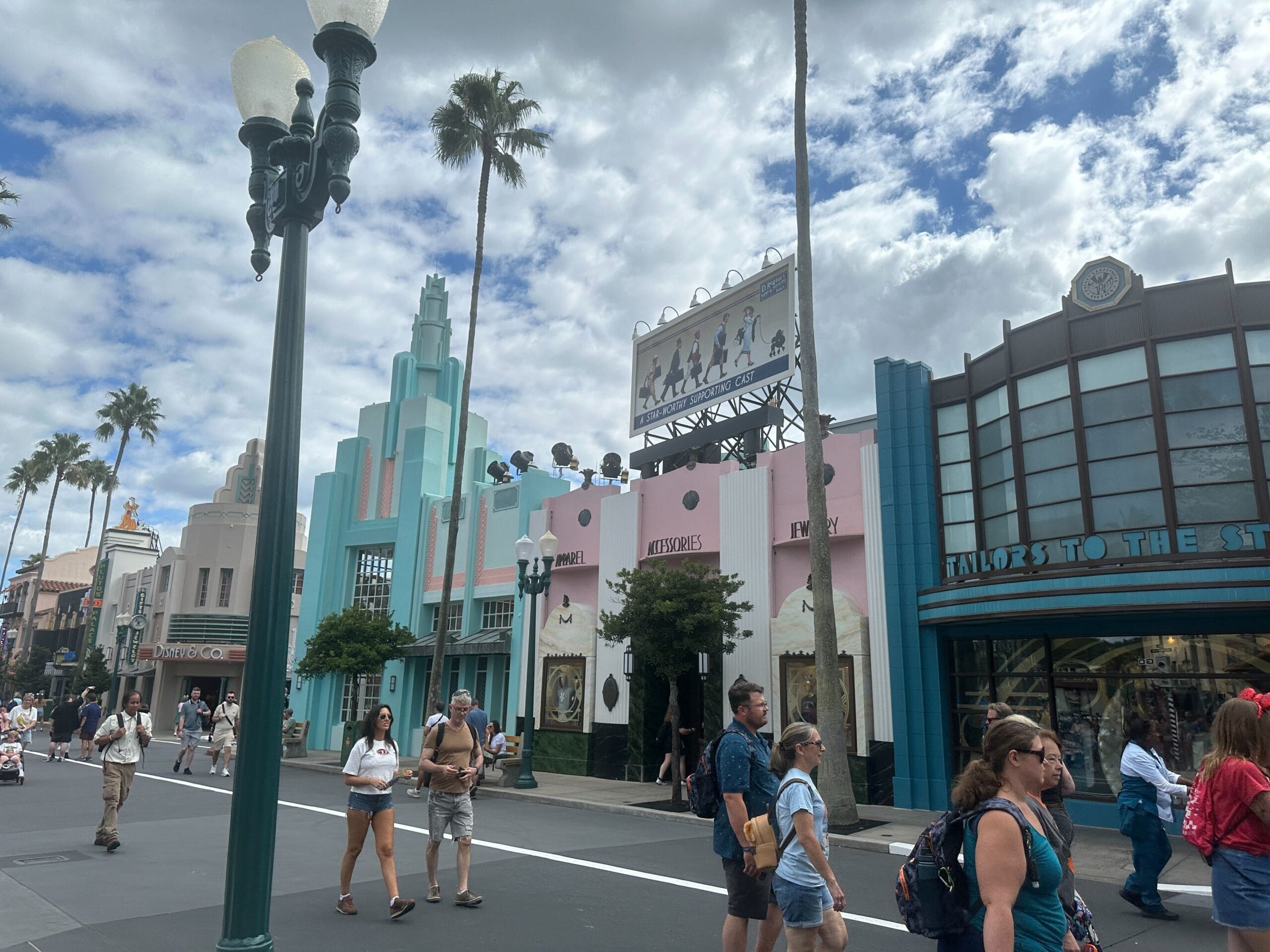Guests stroll down a lively street with art deco facades, festive holiday décor, evoking the charm of Disney’s Hollywood Studios.