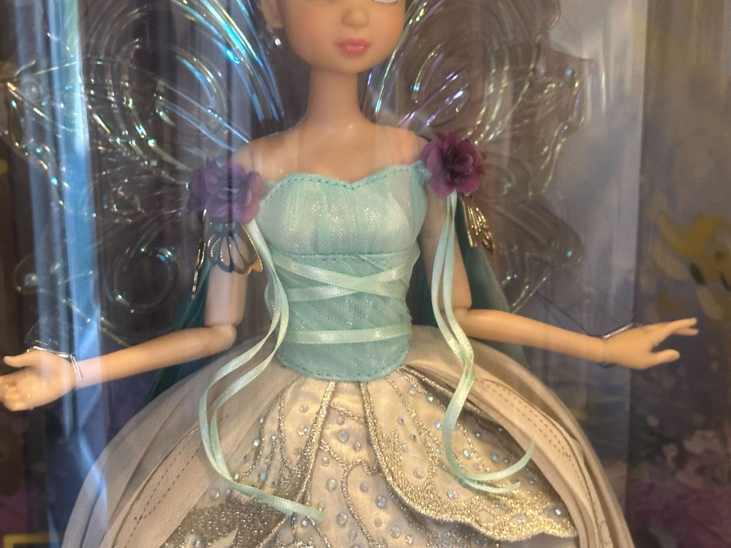 A Designer Tinker Bell fairy doll with silver wings, blue and white dress, and purple flower straps, boxed as in Disney park shops.