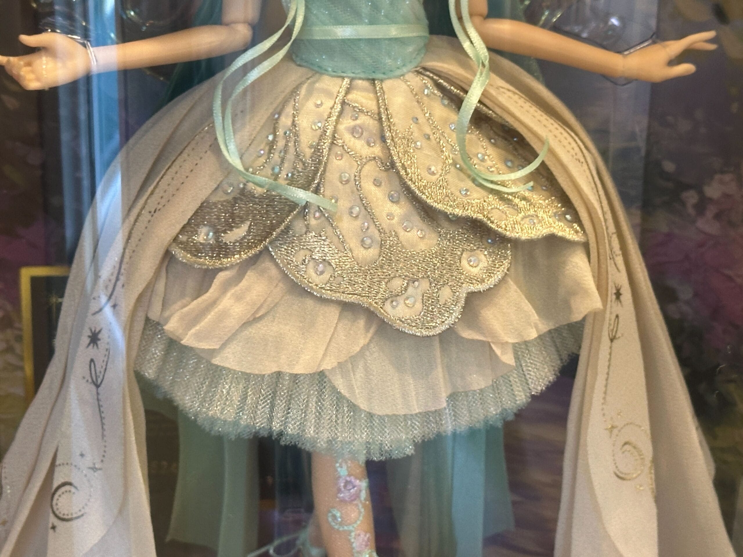 A Designer Tinker Bell doll in a sparkly blue and white dress with silver embroidery and flowing ribbons, reminiscent of Disney park parades.