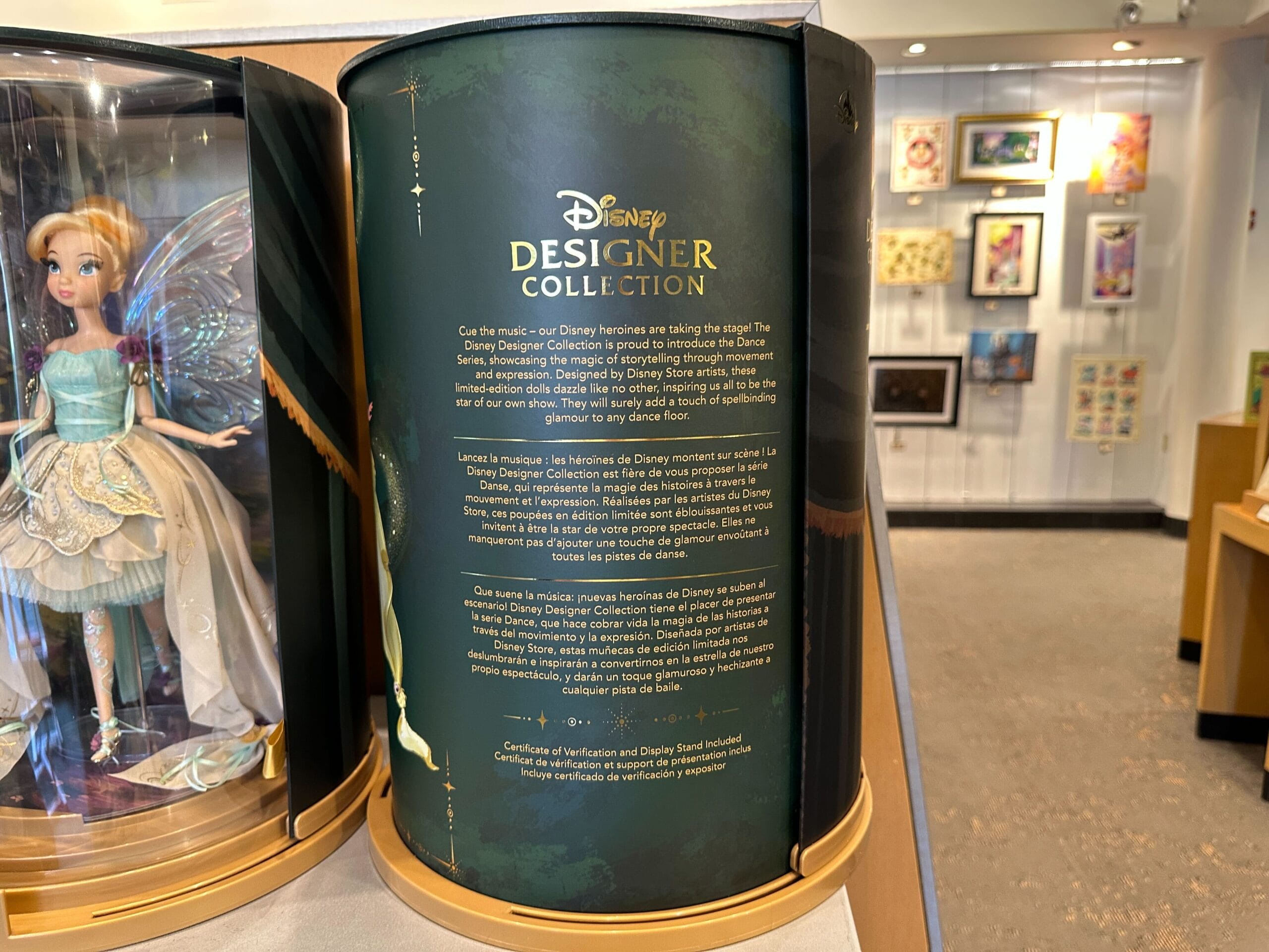A Disney park store display with Designer Tinker Bell packaging and text, next to a fairy doll—no castle like Disney parks’ icons shown.