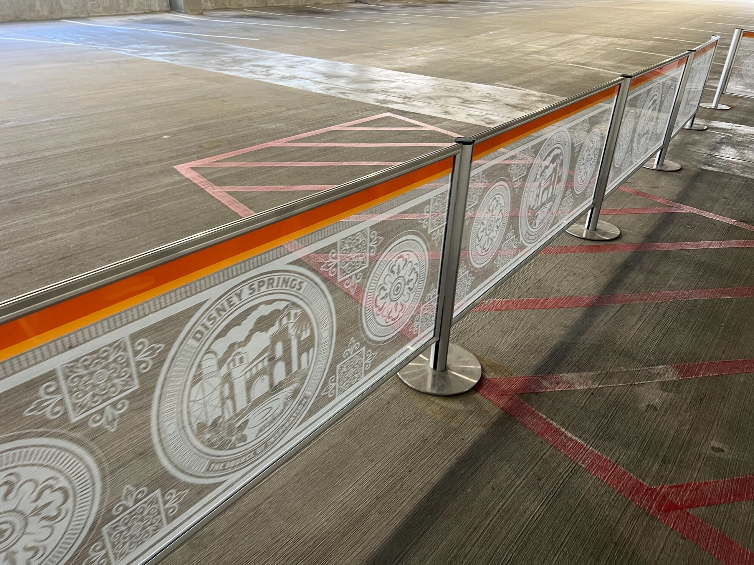 A parking garage at Disney Springs with a themed barrier, orange stripe, and whimsical Disney-inspired decor—no castle in sight.