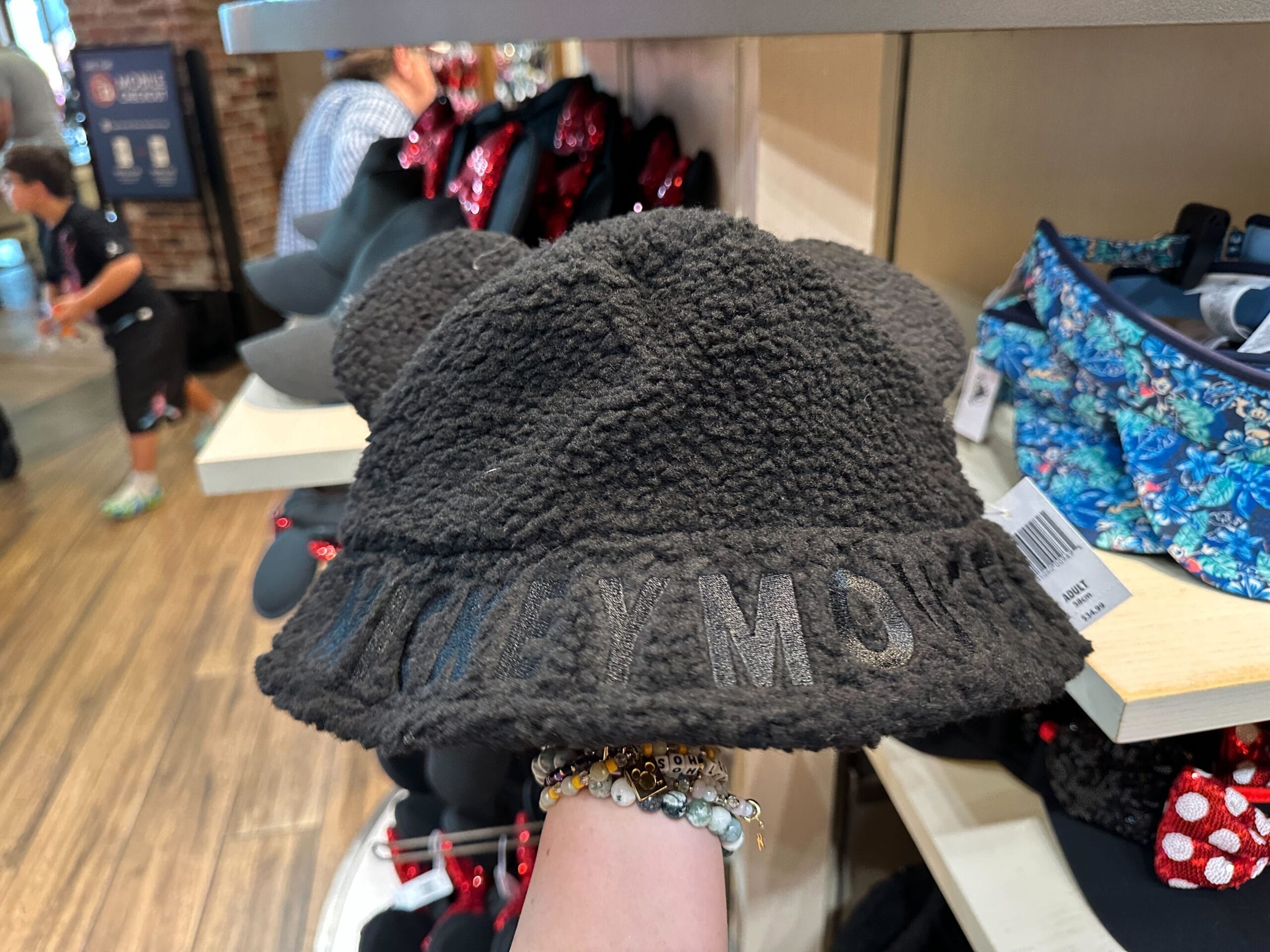 A hand shows a cozy gray Mickey Mouse Sherpa hat with ears—ideal for chilly visits to Disney parks like Walt Disney World.