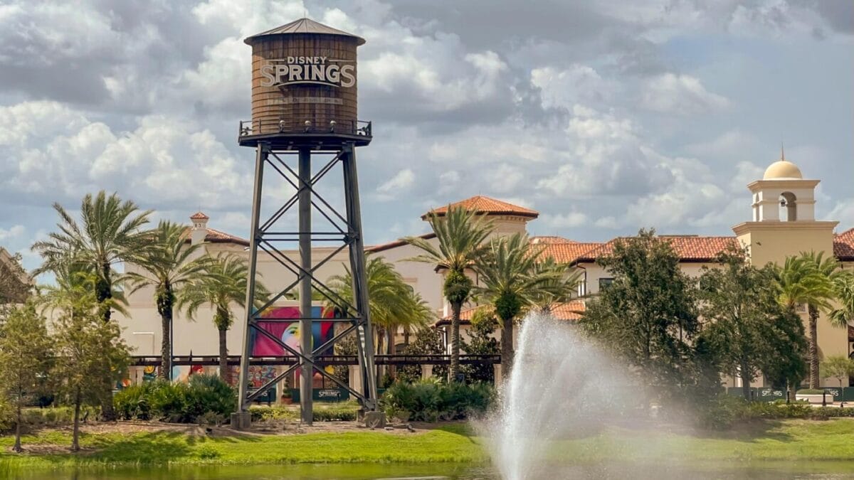 A tall Disney Springs water tower rises beside palm trees and a fountain—no castle here, but classic Disney Springs scenery.