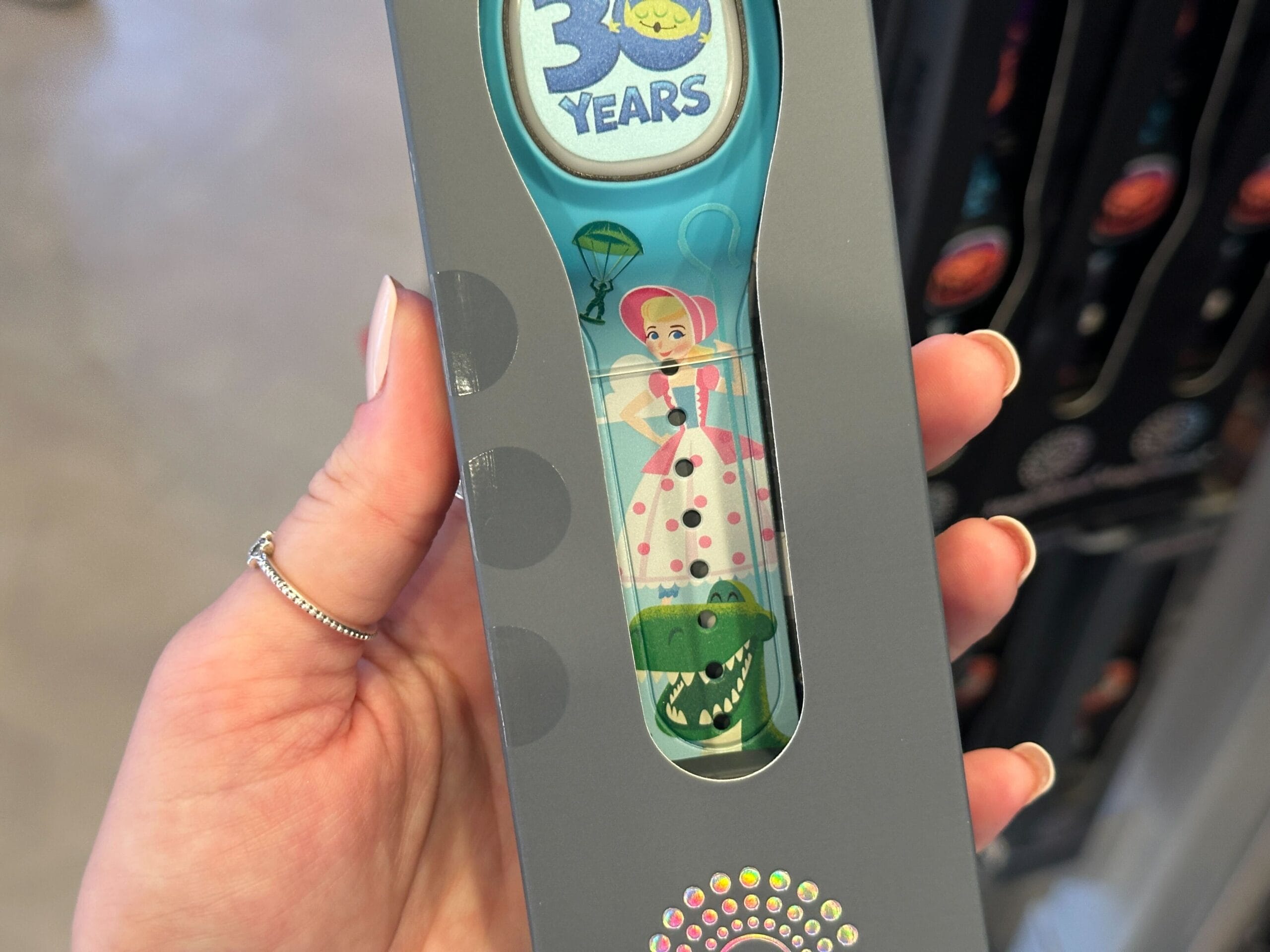 A hand holds a Toy Story toothbrush with Bo Peep and Rex, plus a "30 years" emblem near the top.