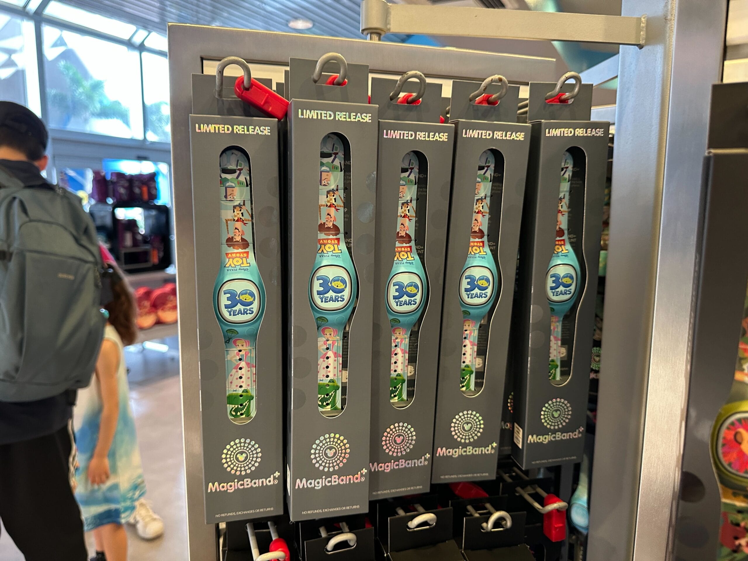 Five MagicBand+ designs for the 30th anniversary of "A Goofy Movie" are displayed on a store rack.