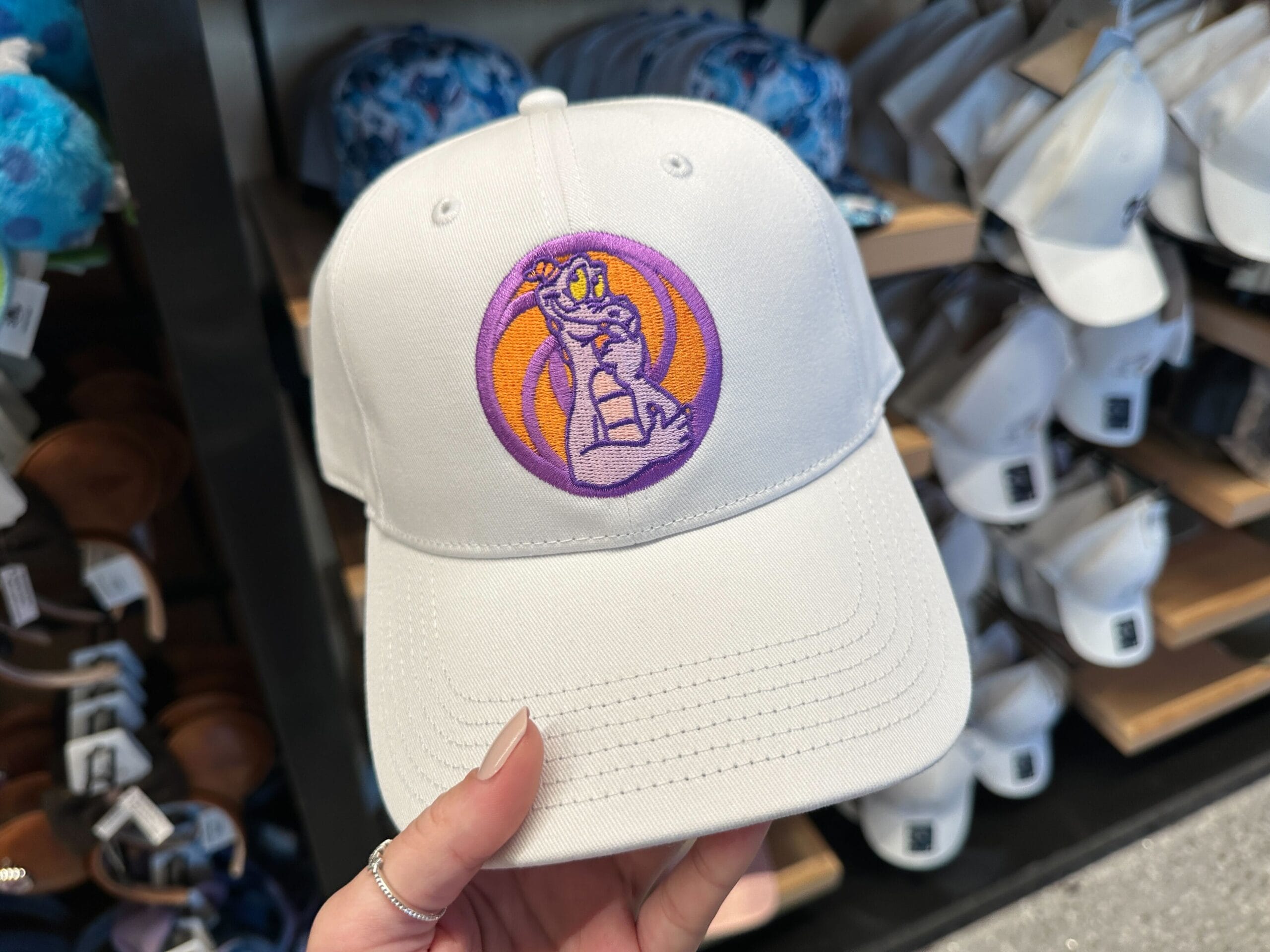 White Figment Baseball Cap featuring a purple dragon sparks imagination, perfect for Disney World fans, displayed in store.