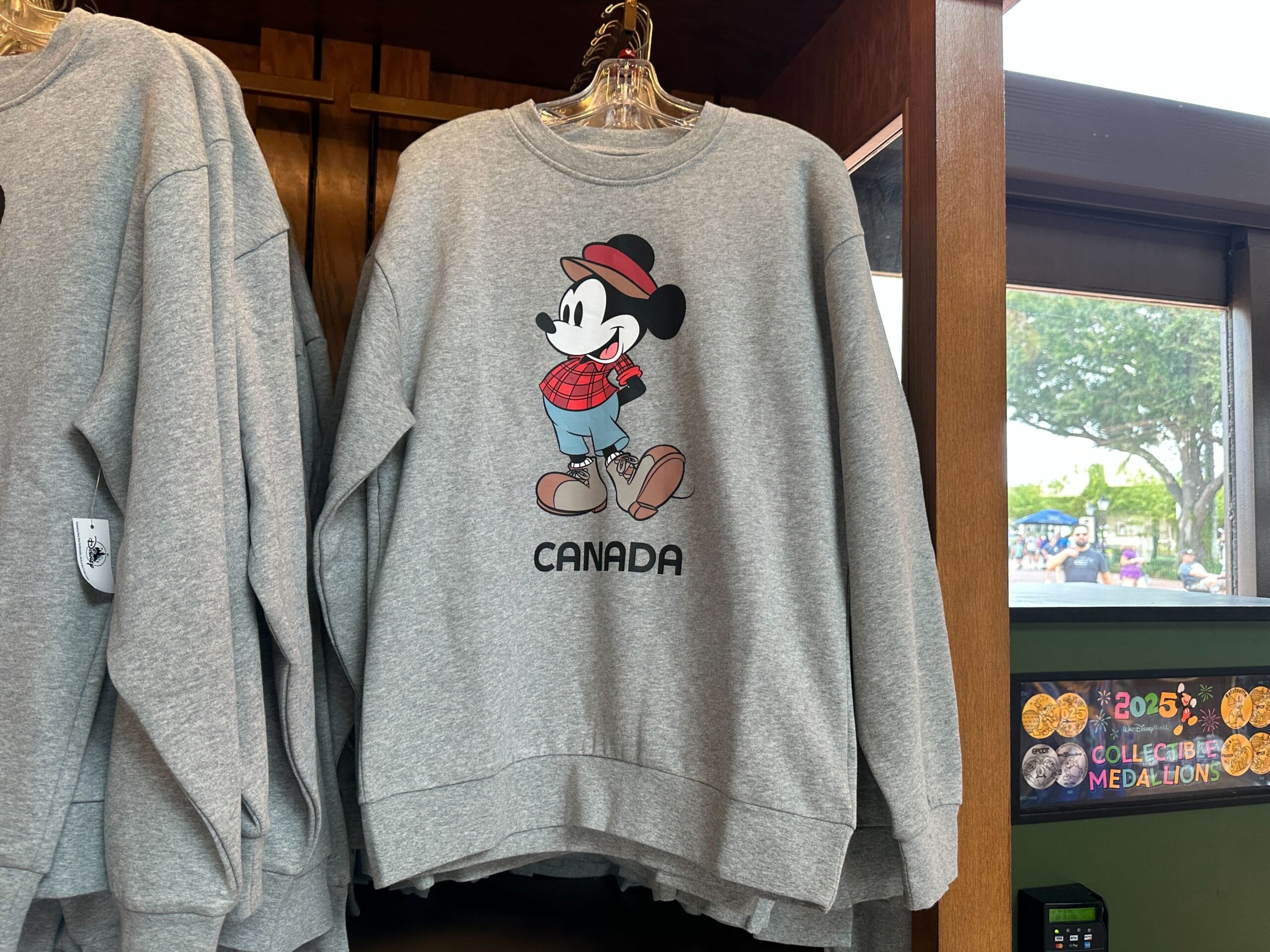 Gray sweatshirt with Mickey Mouse in plaid labeled "CANADA," spotted at EPCOT's World Showcase shop.