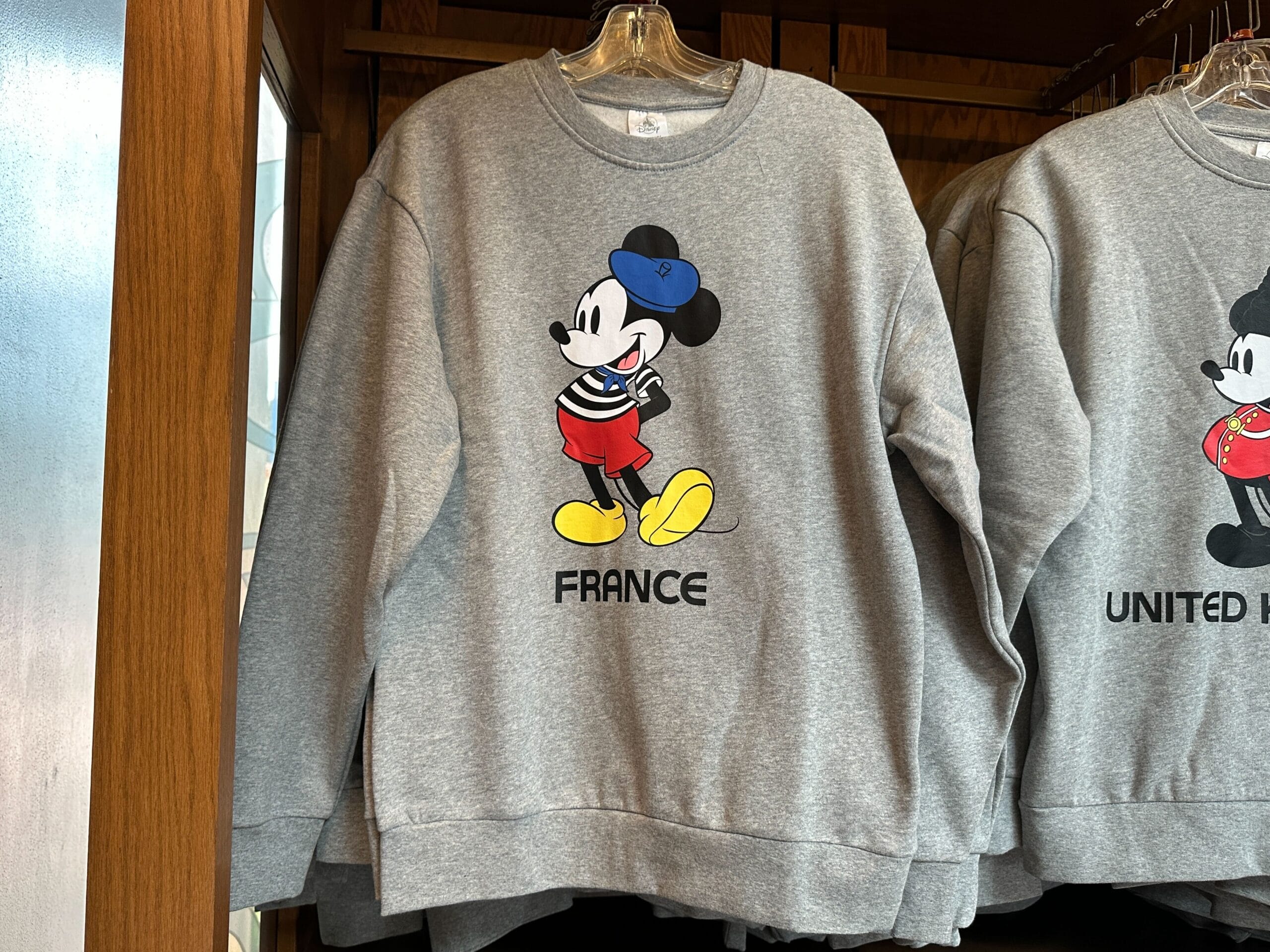 Gray sweatshirt with Mickey Mouse in French attire, labeled "FRANCE," inspired by EPCOT World Showcase.