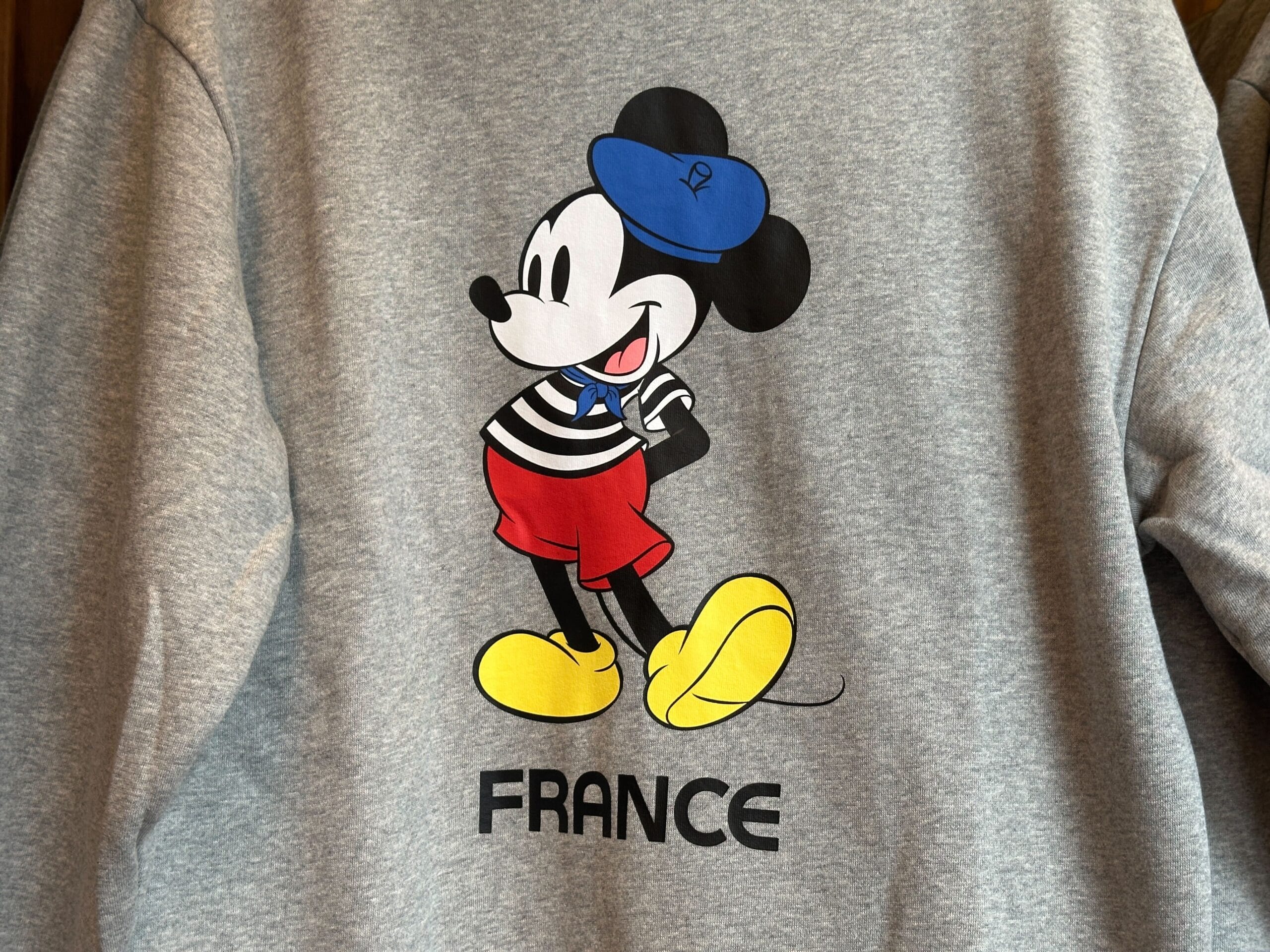 Mickey Mouse in French attire with "FRANCE" below, part of the EPCOT Sweatshirt Collection on a gray sweatshirt.