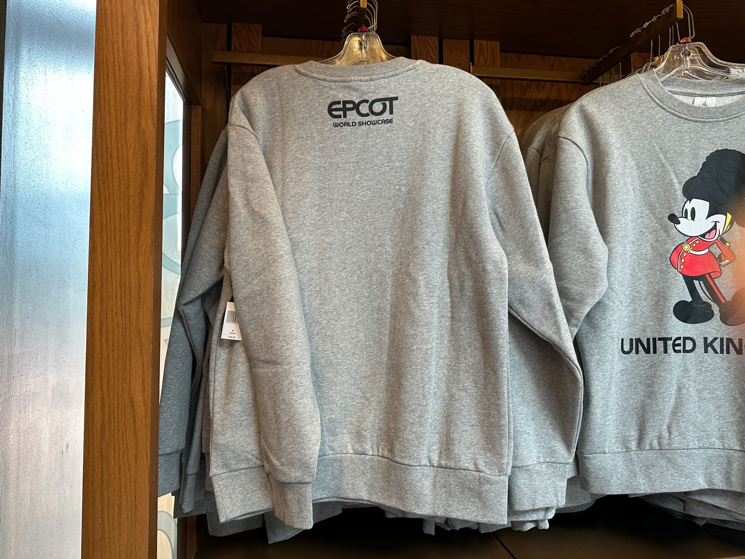Gray sweatshirt with "EPCOT World Showcase" text on the back, hanging next to a Mickey Mouse UK sweatshirt.