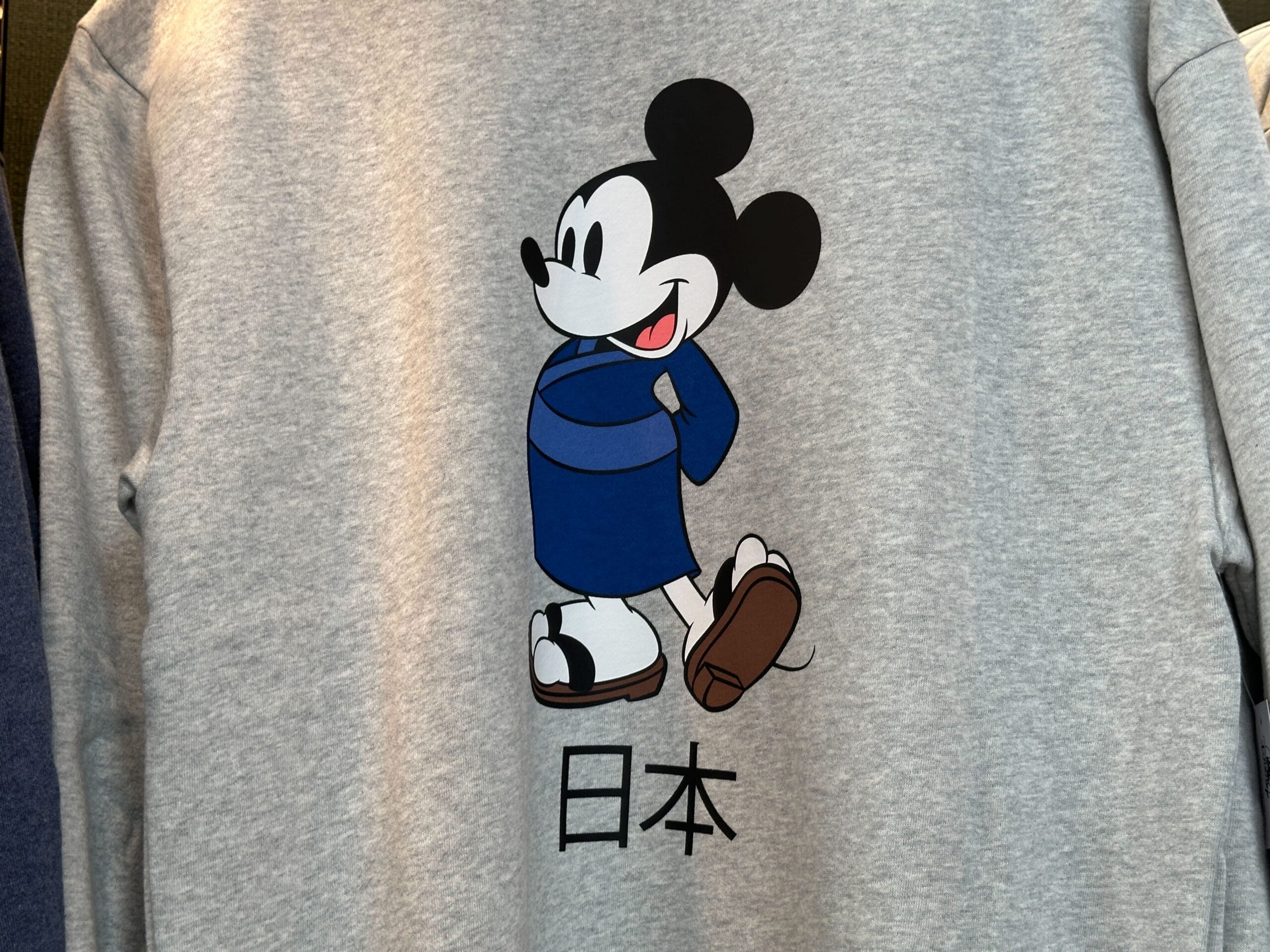 Mickey Mouse in a blue kimono with "Japan" below, part of the EPCOT Sweatshirt Collection on a gray shirt.
