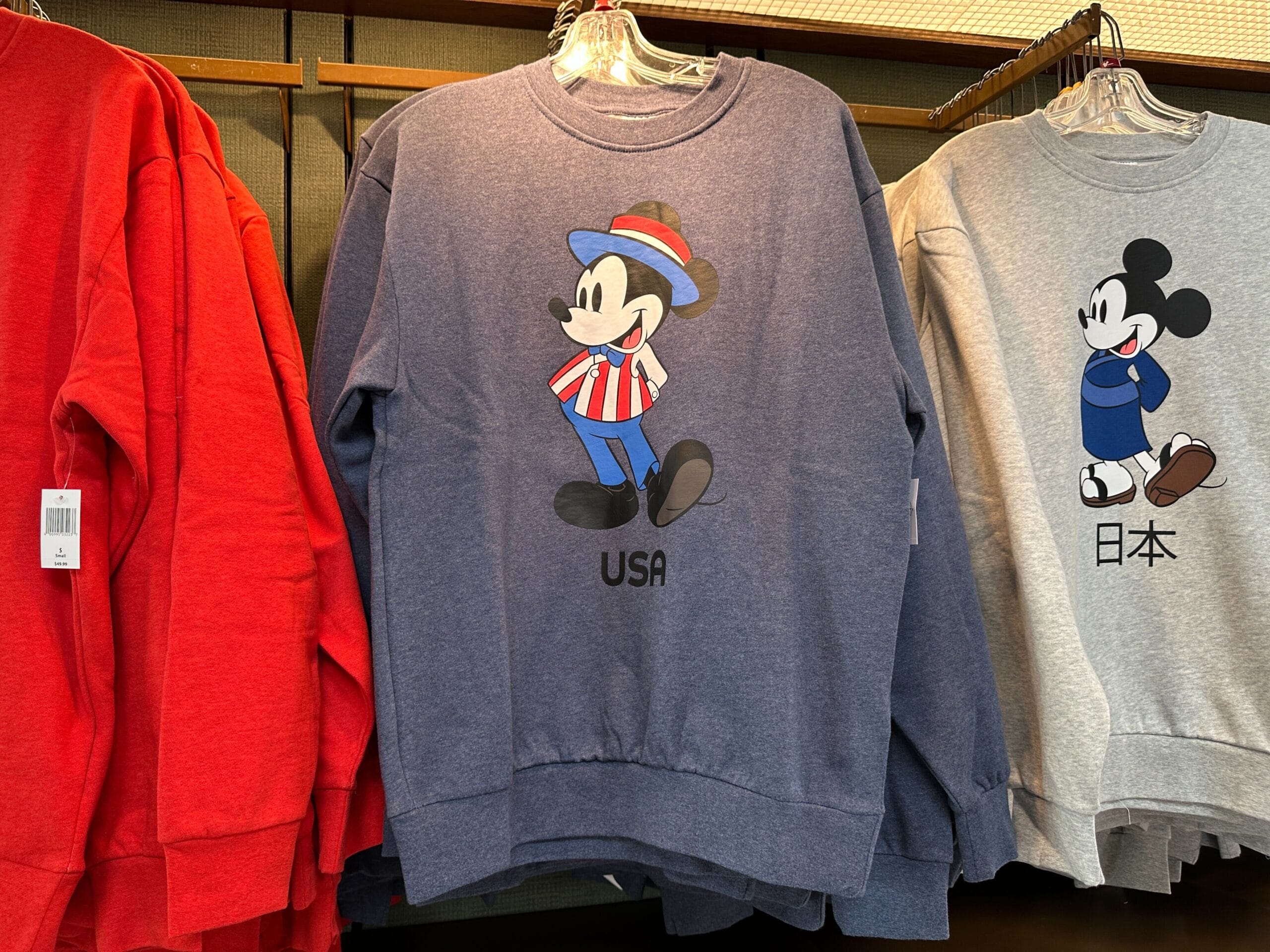 Blue sweatshirt with Mickey Mouse in USA-themed outfit; gray EPCOT sweatshirt with Mickey Mouse and Japanese text.
