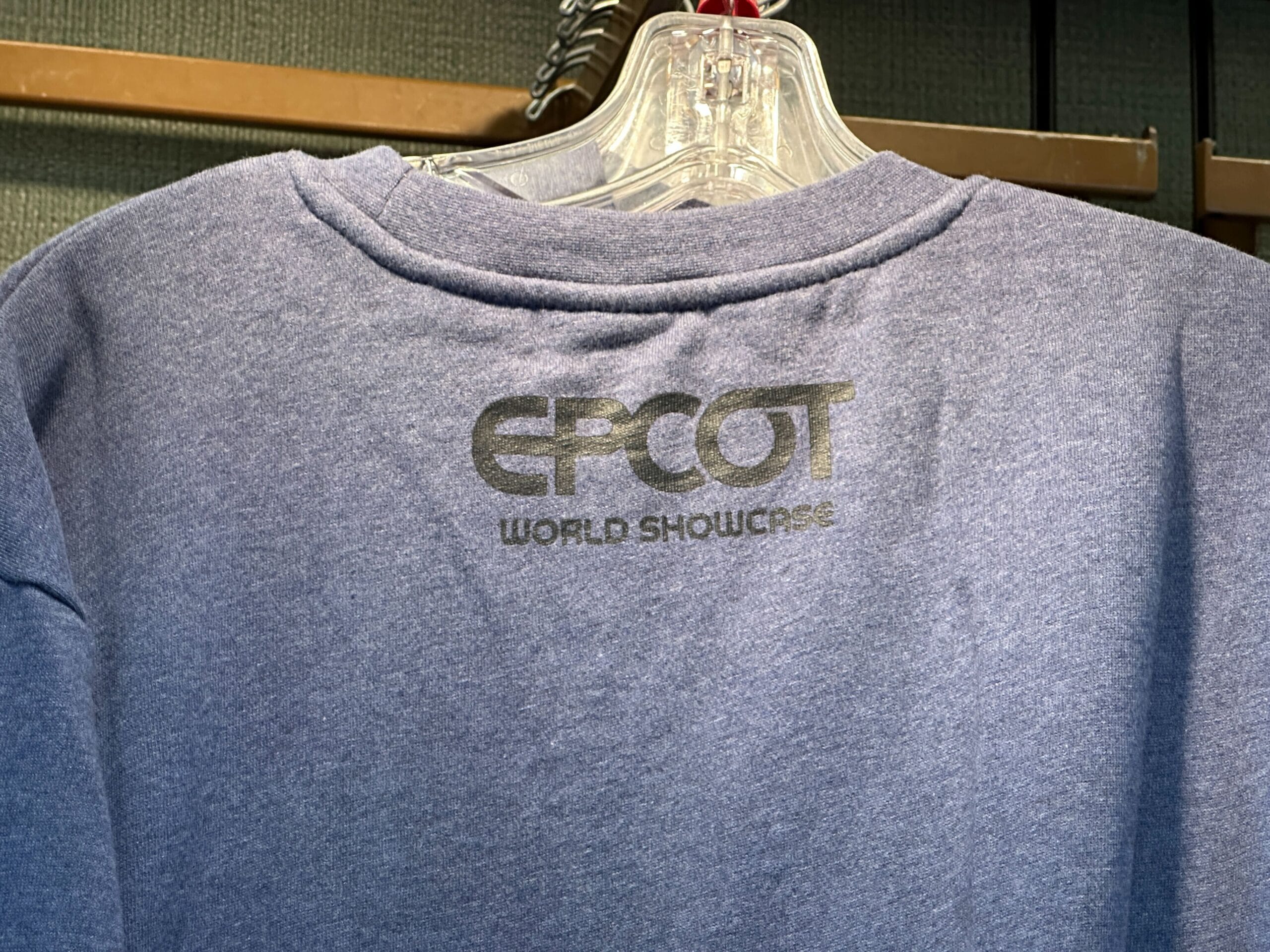 A blue shirt on a hanger with "EPCOT World Showcase" in silver, perfect for any Mickey Mouse fan.