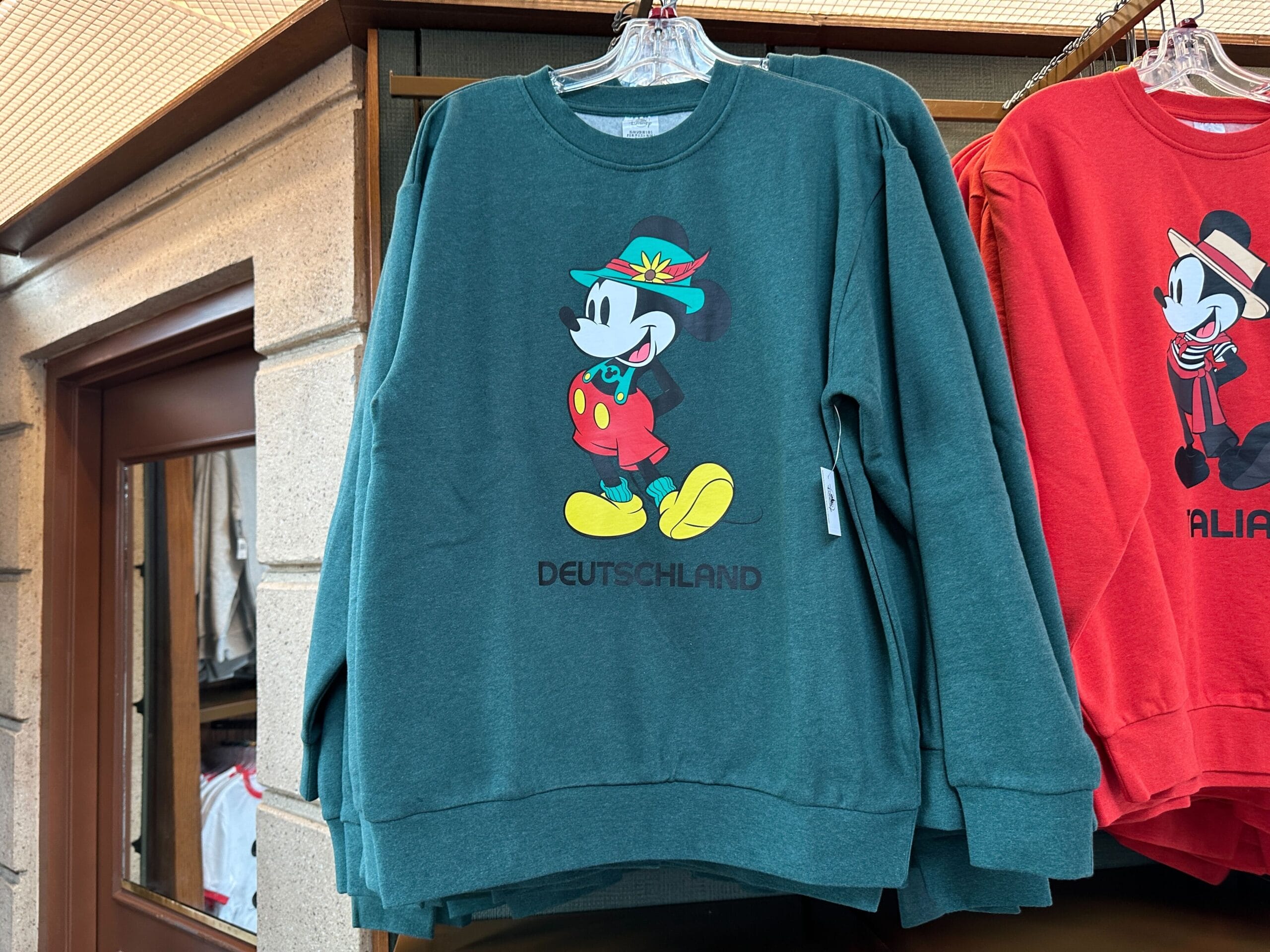 Green Mickey Mouse sweatshirt from the EPCOT Sweatshirt Collection, featuring German attire and "DEUTSCHLAND" below.