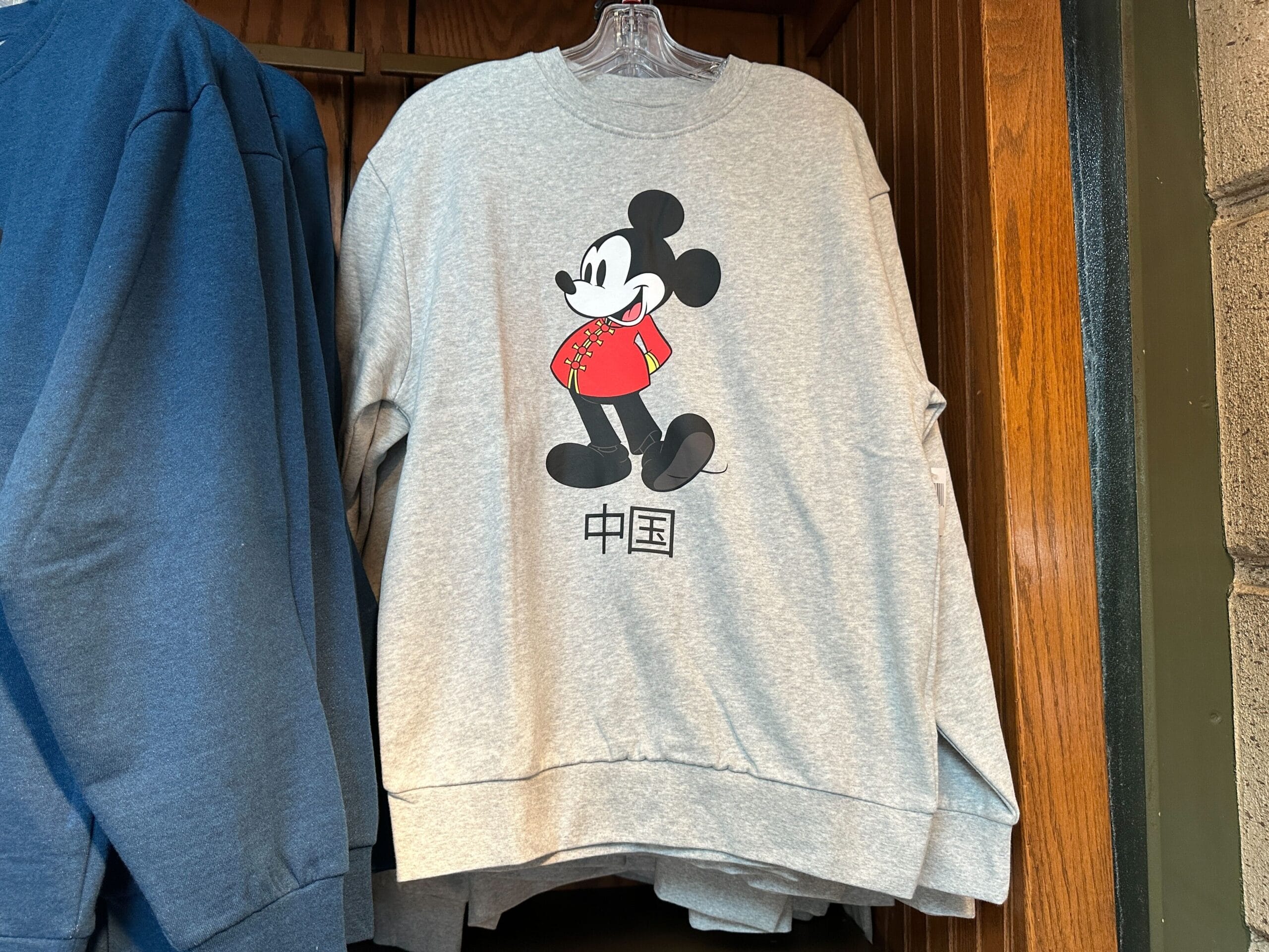 A gray sweatshirt featuring Mickey Mouse in a red shirt with Chinese characters, inspired by EPCOT’s World Showcase.