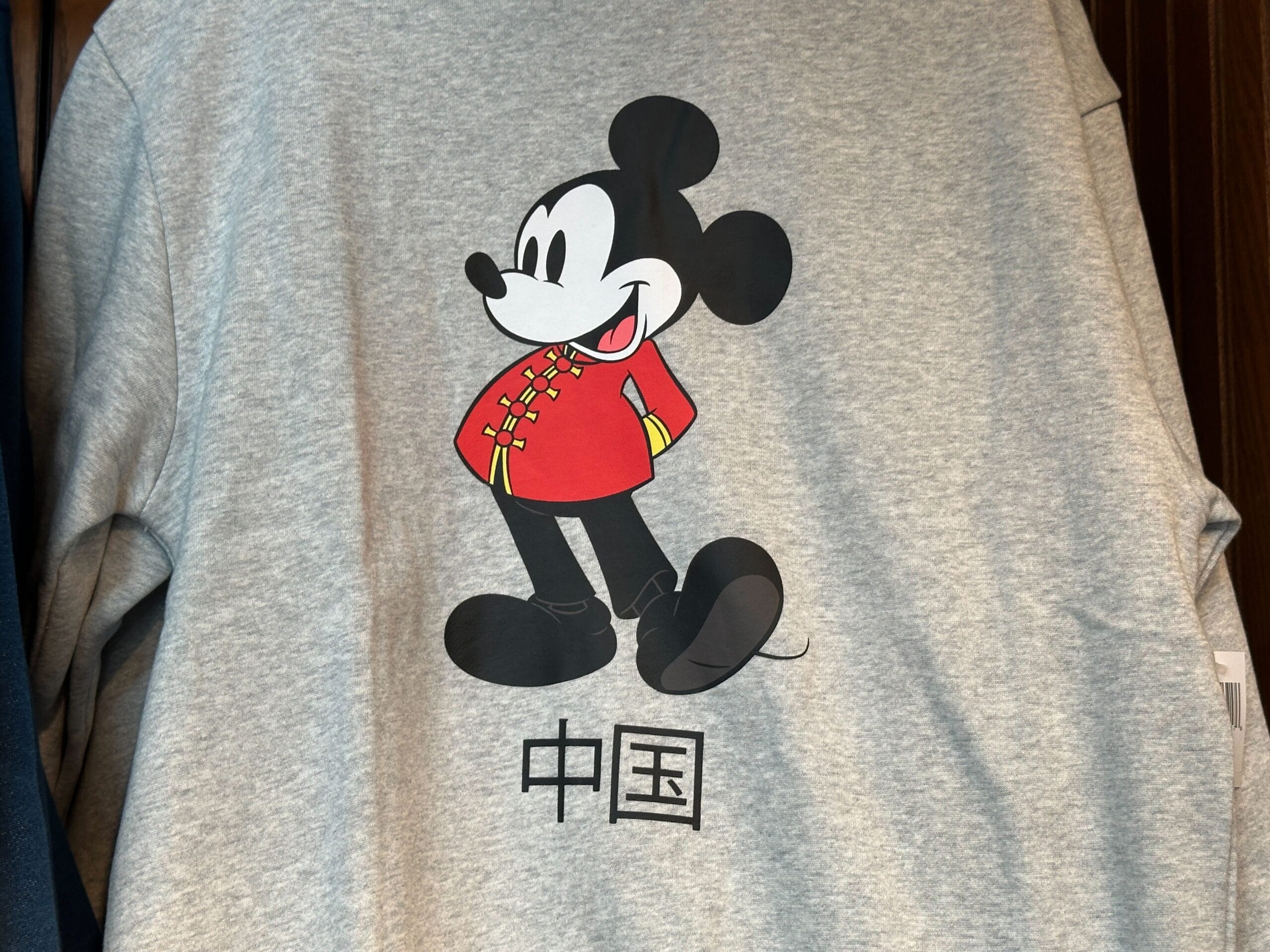 Mickey Mouse in a red Chinese jacket on a gray shirt, part of the EPCOT Sweatshirt Collection, with "China" in Chinese below.
