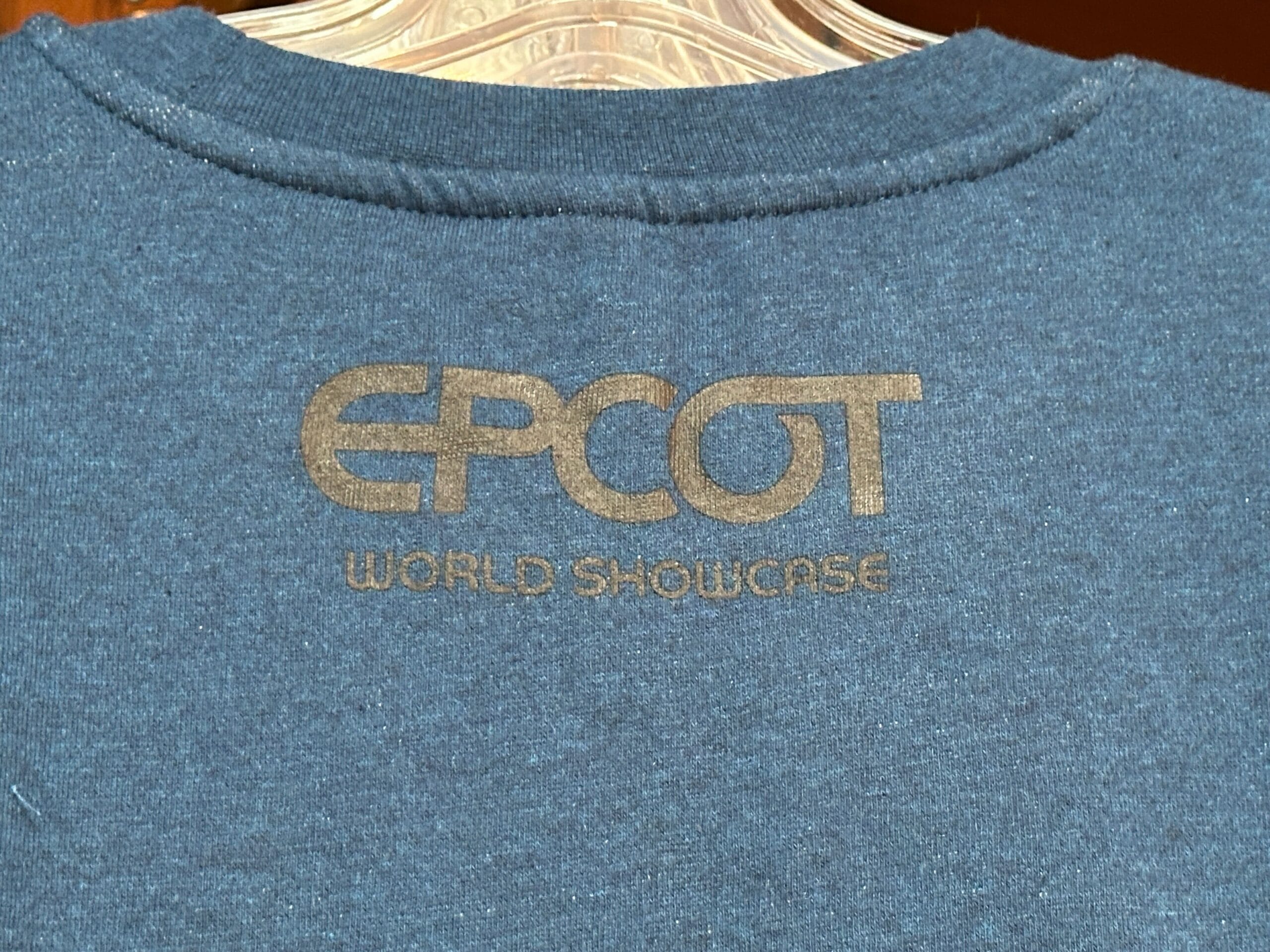 Blue shirt from the EPCOT Sweatshirt Collection with "EPCOT WORLD SHOWCASE" printed in gold on the back.
