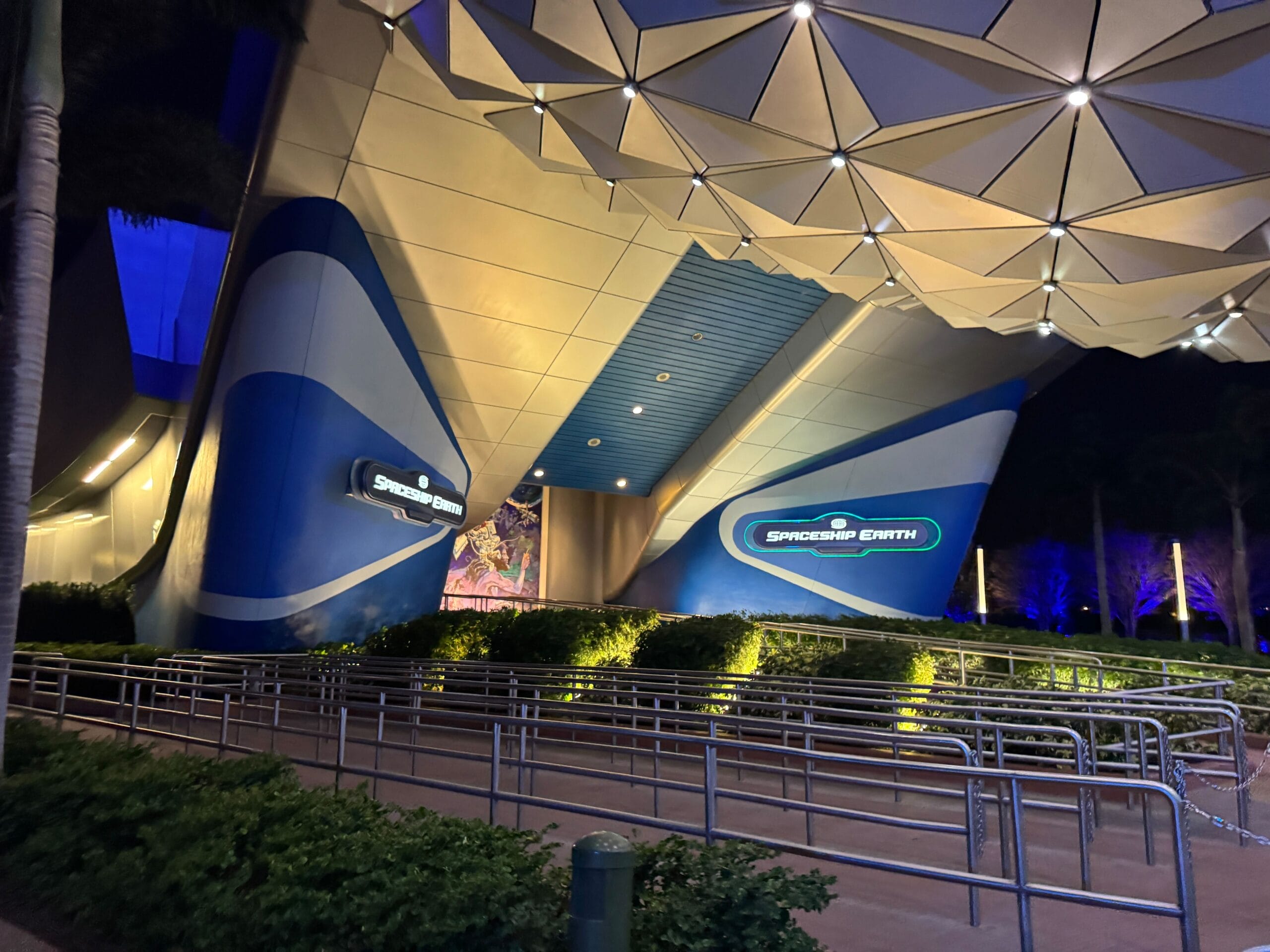 Spaceship Earth’s entrance at night glows with new Epcot lighting and sleek design—no castle, just iconic geodesic curves.