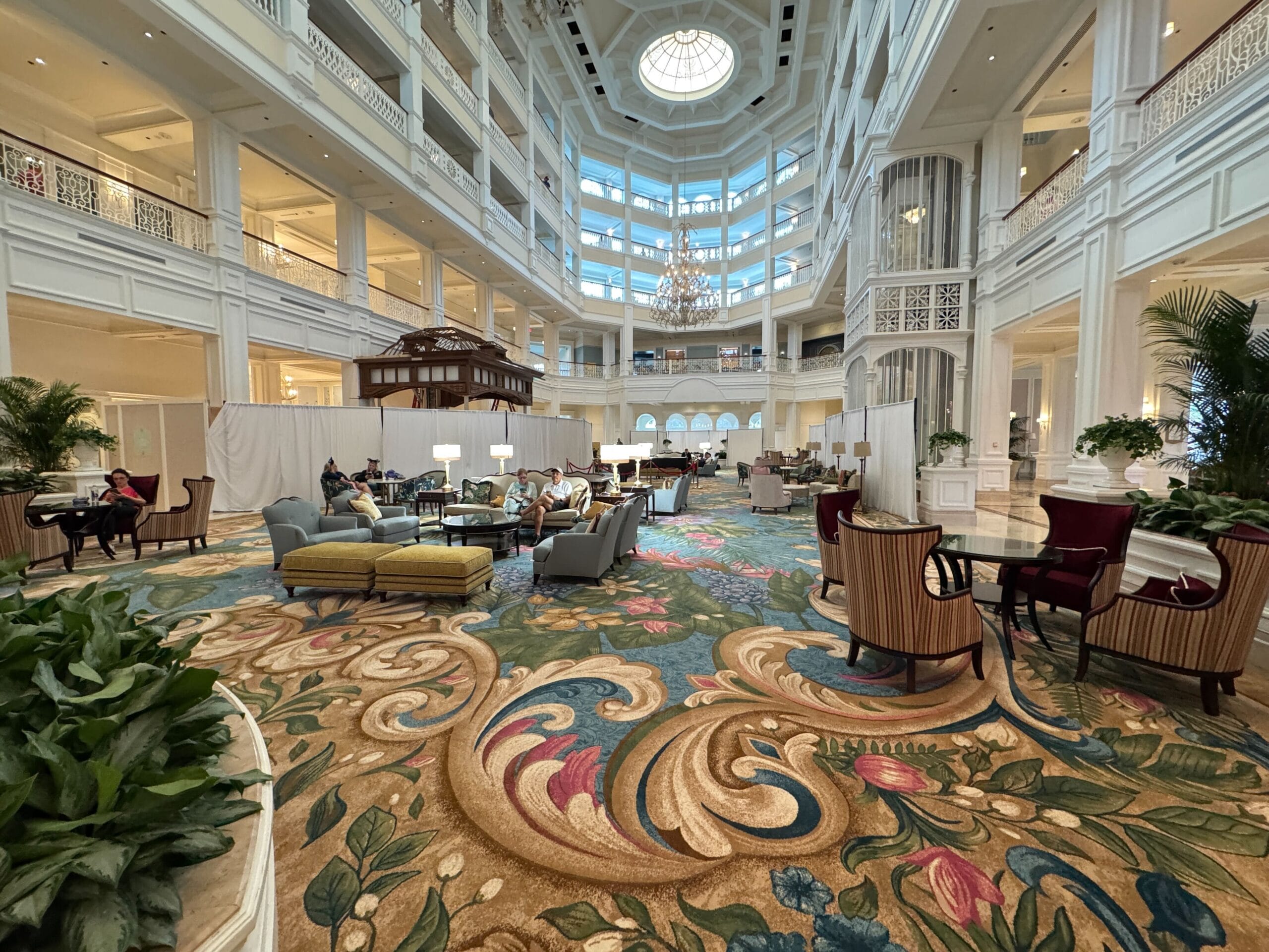 Grand Floridian Resort’s grand lobby with ornate carpet, elegant chairs, soaring ceilings, and bright natural light, Disney luxury style.