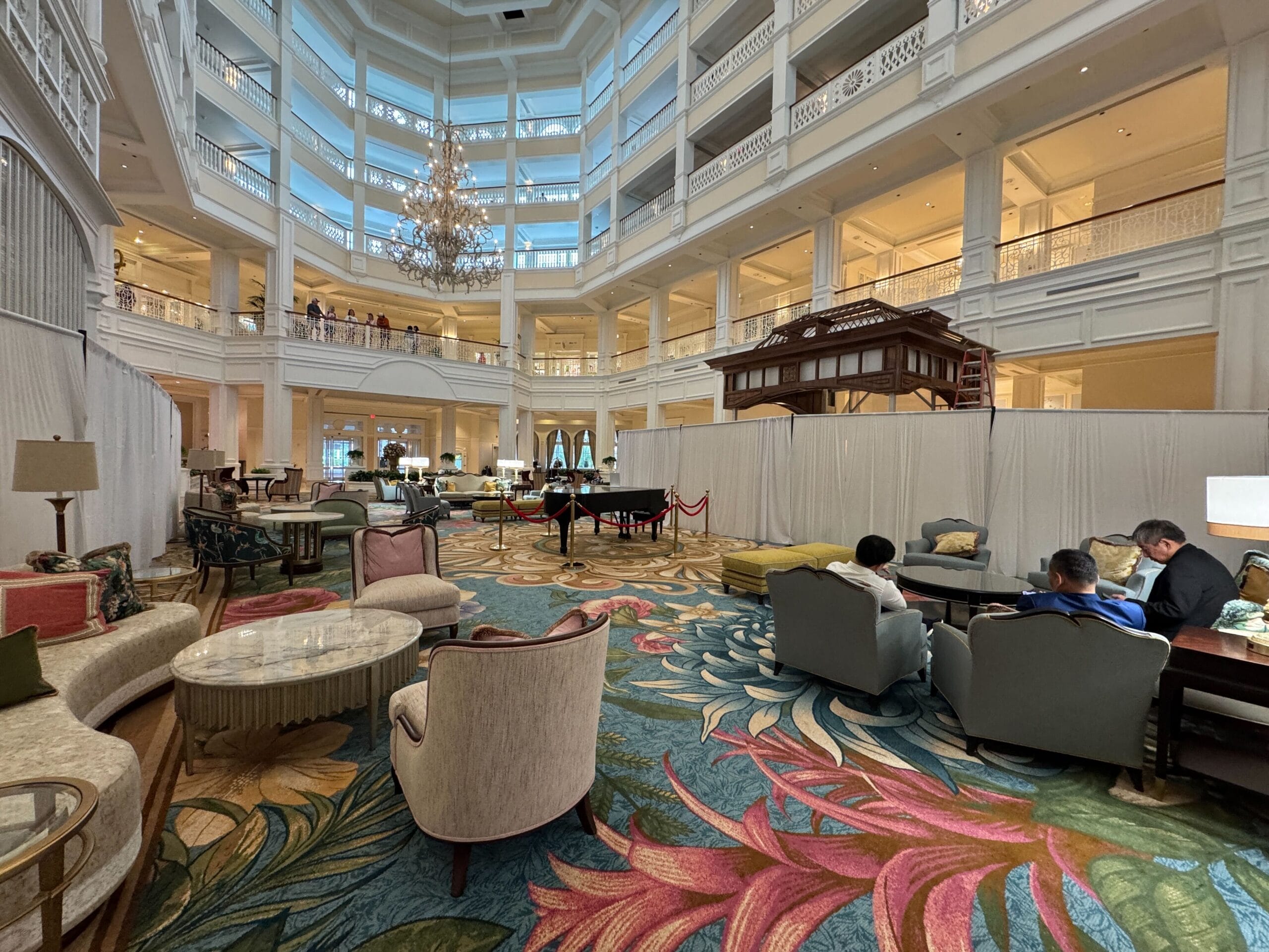 Elegant Grand Floridian lobby with luxurious seating, floral carpet, grand piano, and chandelier, capturing Disney’s signature charm.
